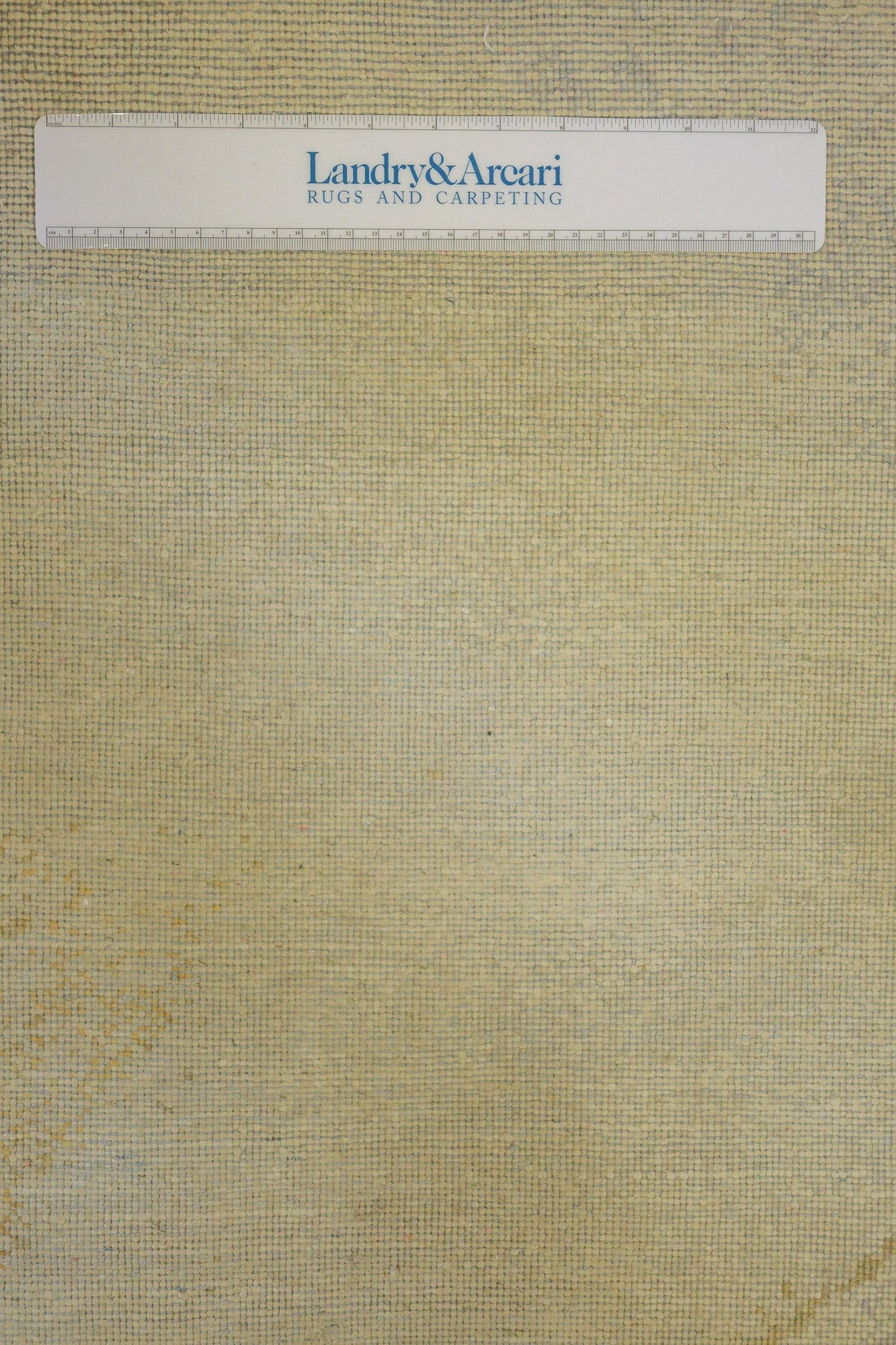 Close-up of beige handwoven rug texture, showing detailed weave.