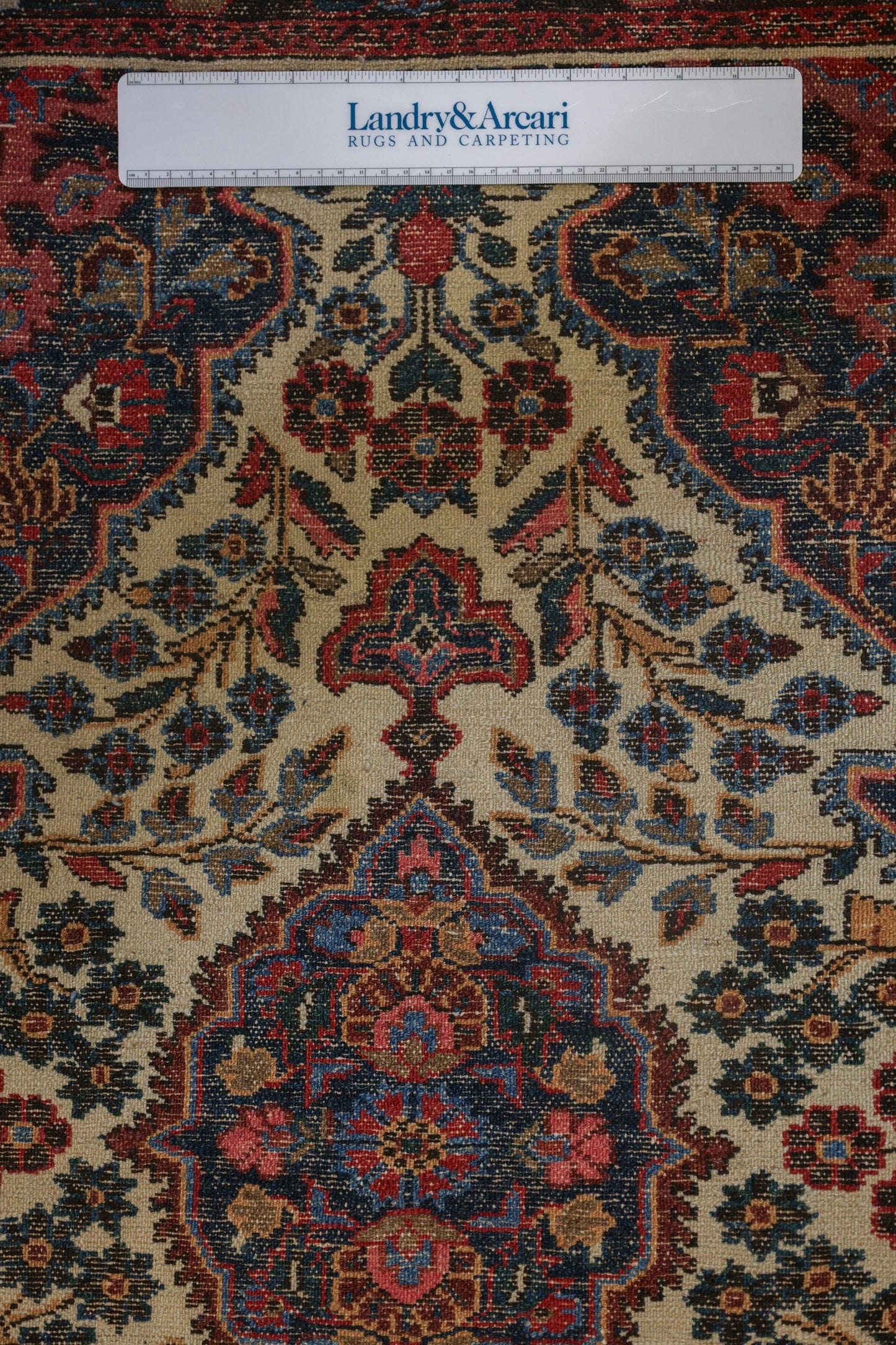 Close-up of antique Dargazine rug detail, showcasing intricate floral pattern in navy, red, and beige.