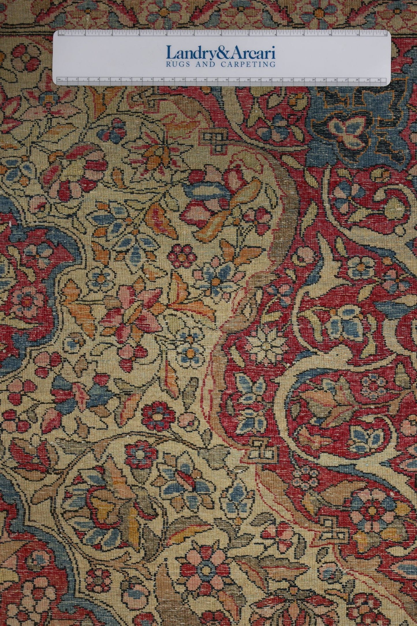 Close-up detail of antique Isfahan rug, showcasing intricate floral pattern in muted reds, blues, and beige.