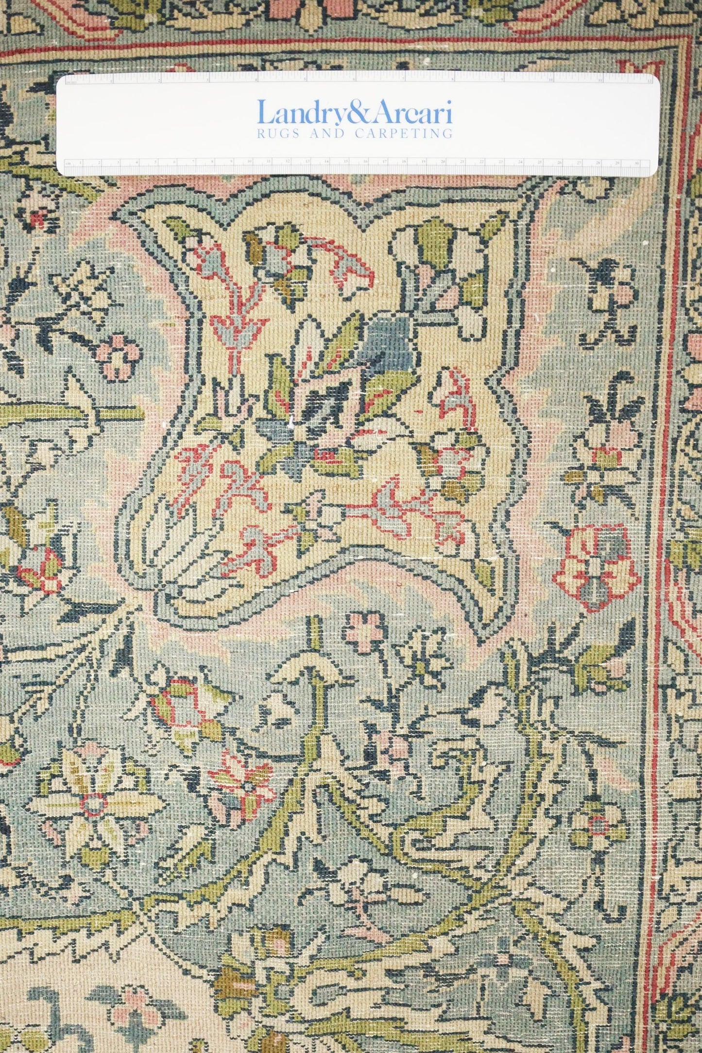 Close-up detail of antique Laristan rug's intricate floral pattern in muted pastel shades.