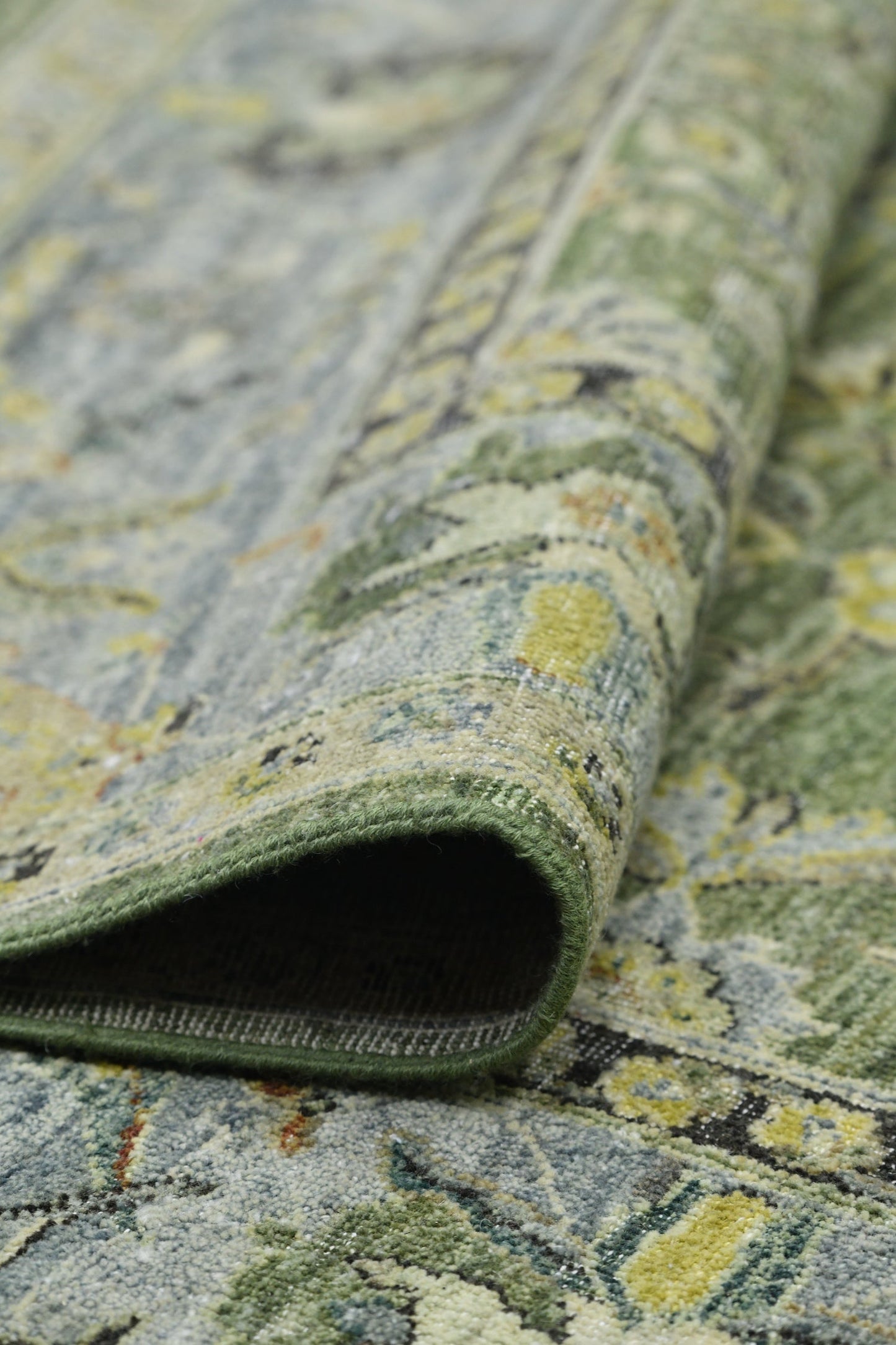 Close-up of a handwoven rug's green and blue patterned texture.