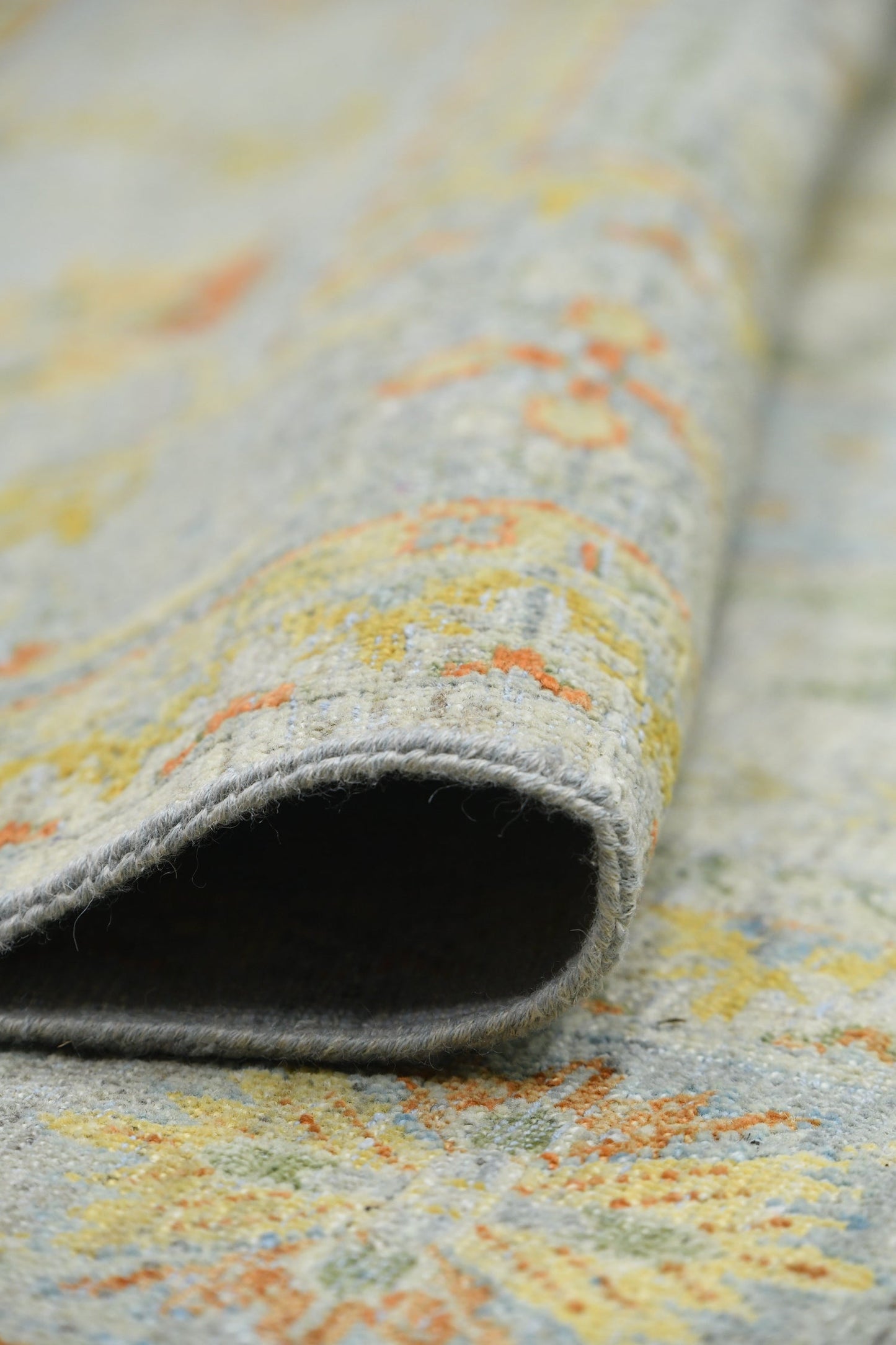 Handwoven rug detail: soft, neutral tones with hints of orange and yellow in a transitional pattern.