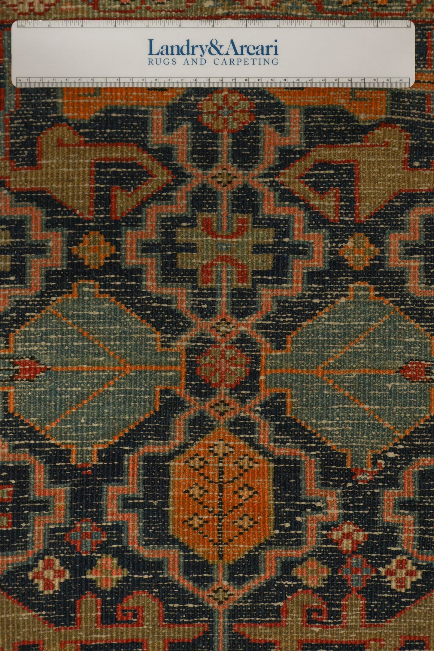 Close-up detail of antique Heriz rug's intricate, handwoven pattern in muted blues, oranges, and greens.