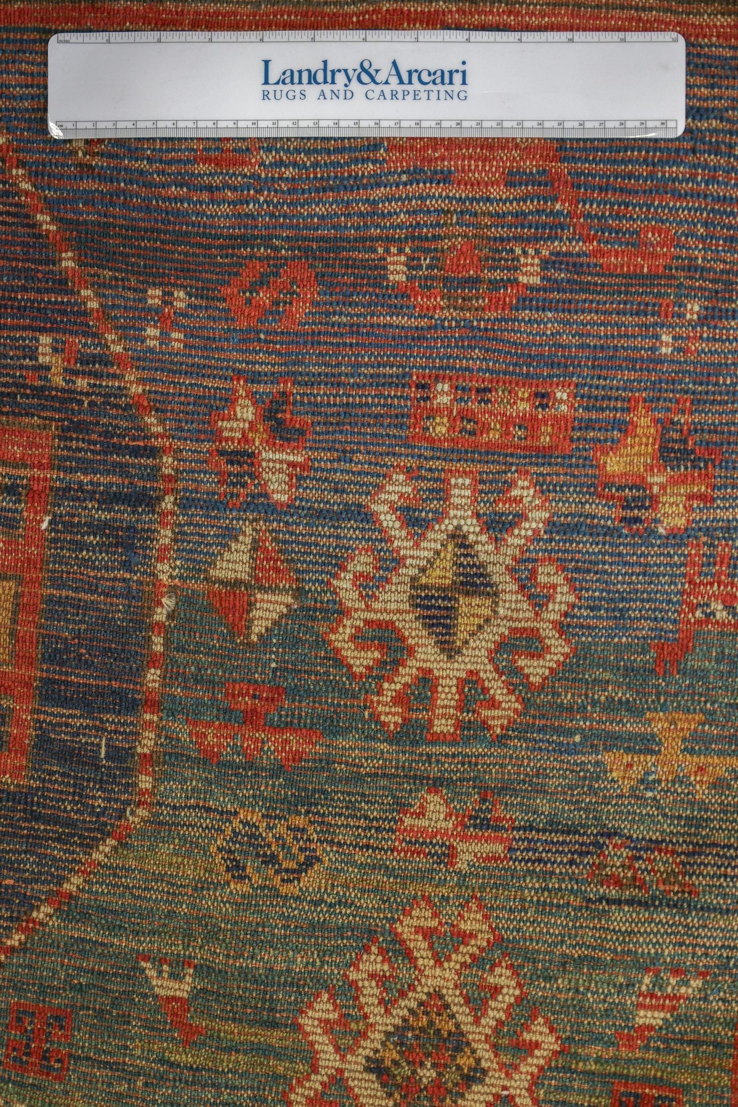 Detailed close-up of an antique Moghan Kazak rug's intricate, handwoven design in rich blues and reds.