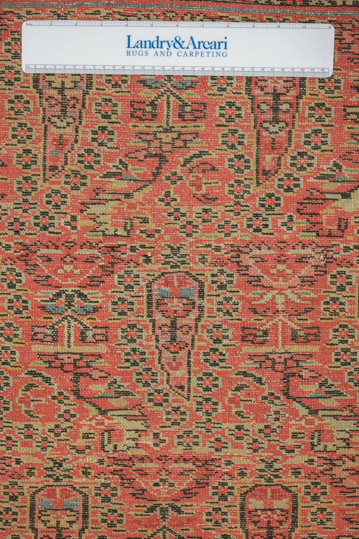 Close-up detail of antique tribal rug's handwoven red and black pattern.
