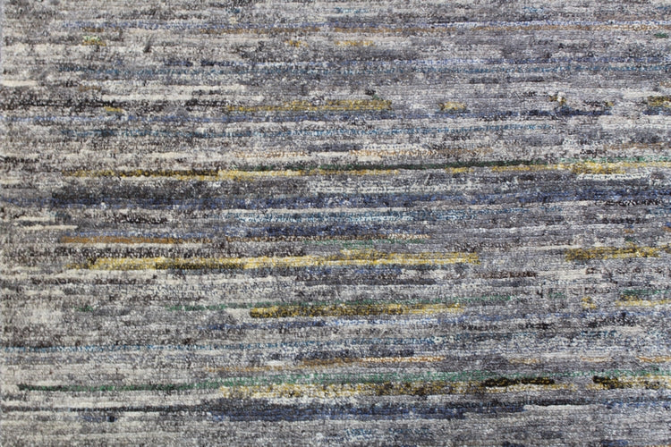 Handwoven rug detail: grey, blue, and yellow striped pattern in contemporary style.