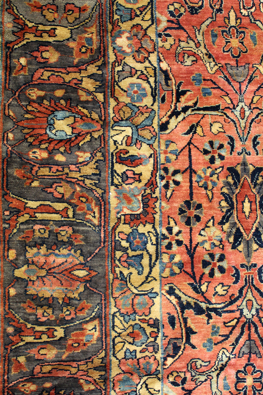 Detail of antique rug's handwoven floral pattern in reds, blues, and golds.