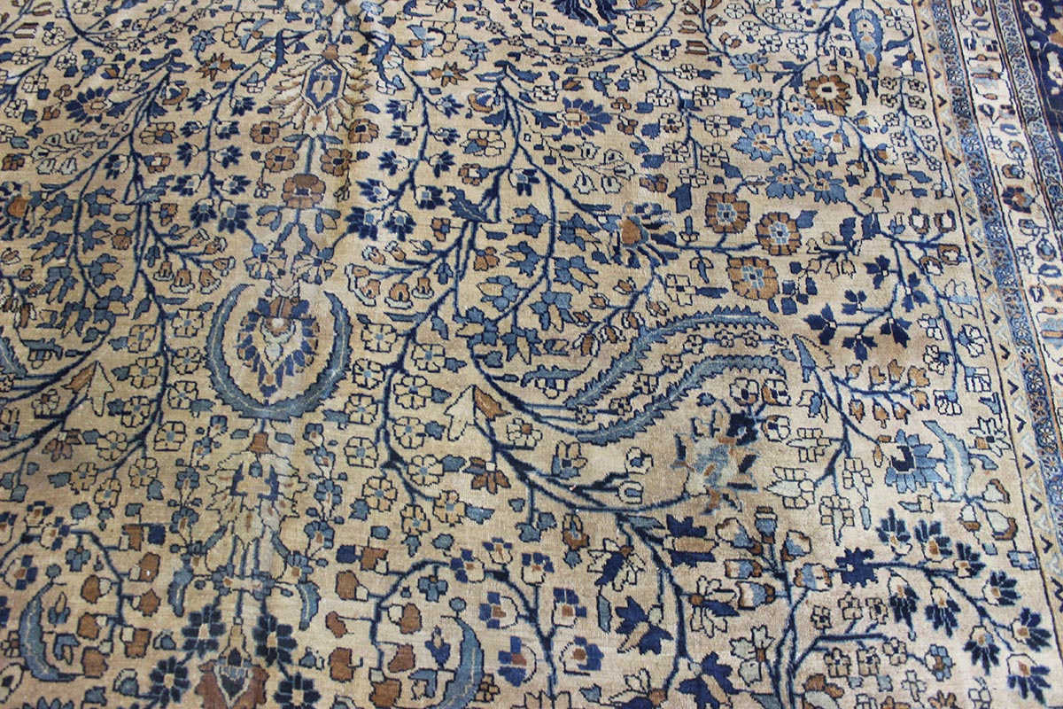Handwoven Mashad rug detail: beige background with blue and brown floral pattern.