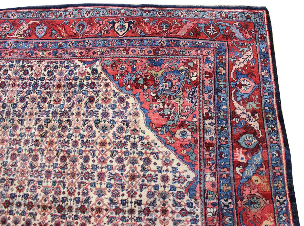 Antique handwoven rug detail, showcasing a red, blue, and ivory floral pattern.
