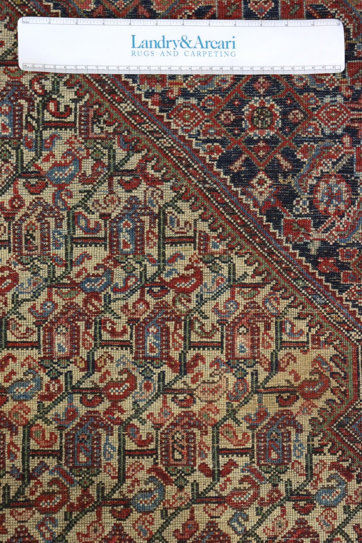 Detailed close-up of antique Bijar rug's intricate handwoven pattern, showcasing reds, blues, and greens.