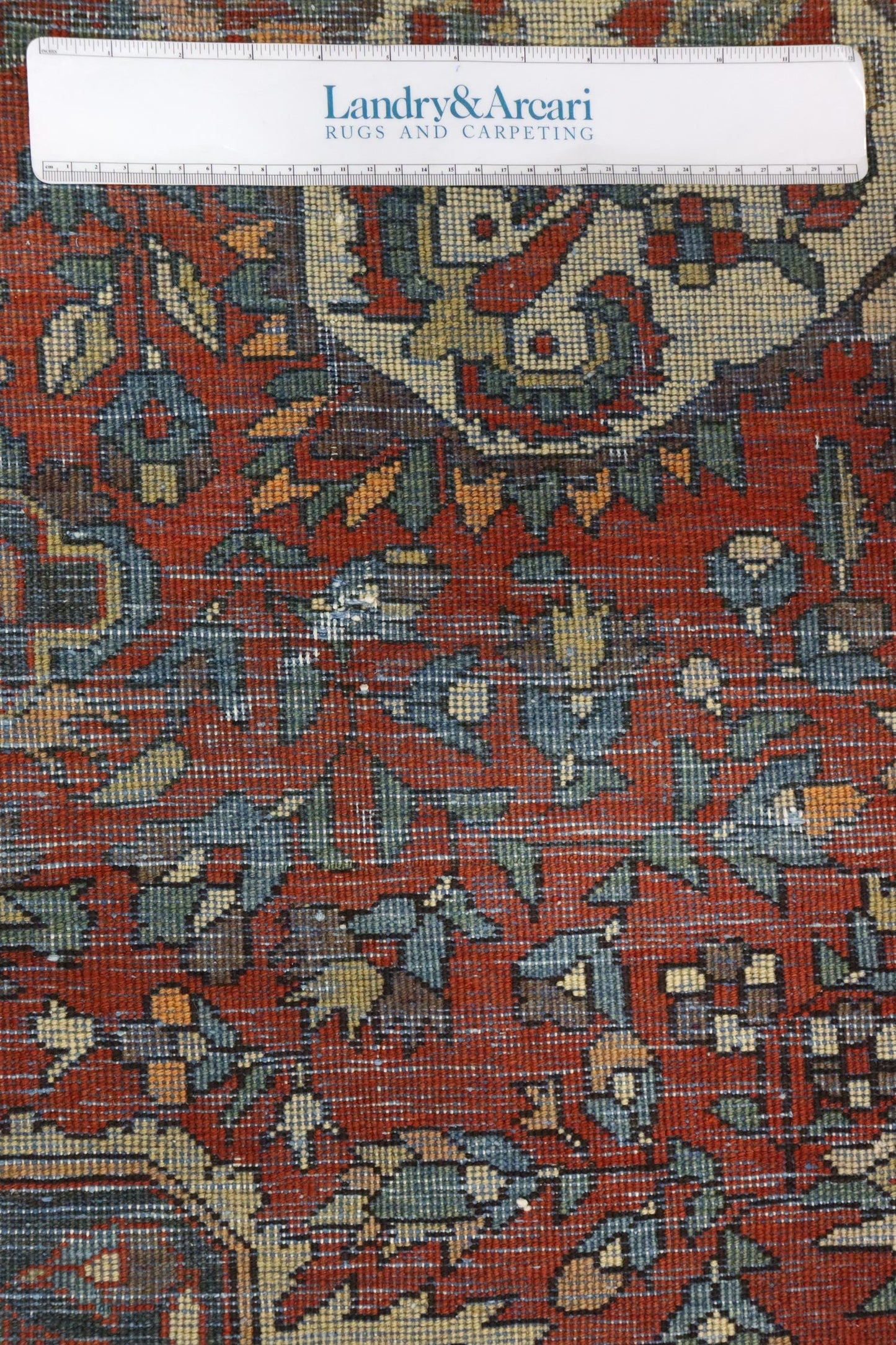 Close-up detail of antique Ferahan rug, showcasing its intricate handwoven pattern in rich reds, blues, and creams.