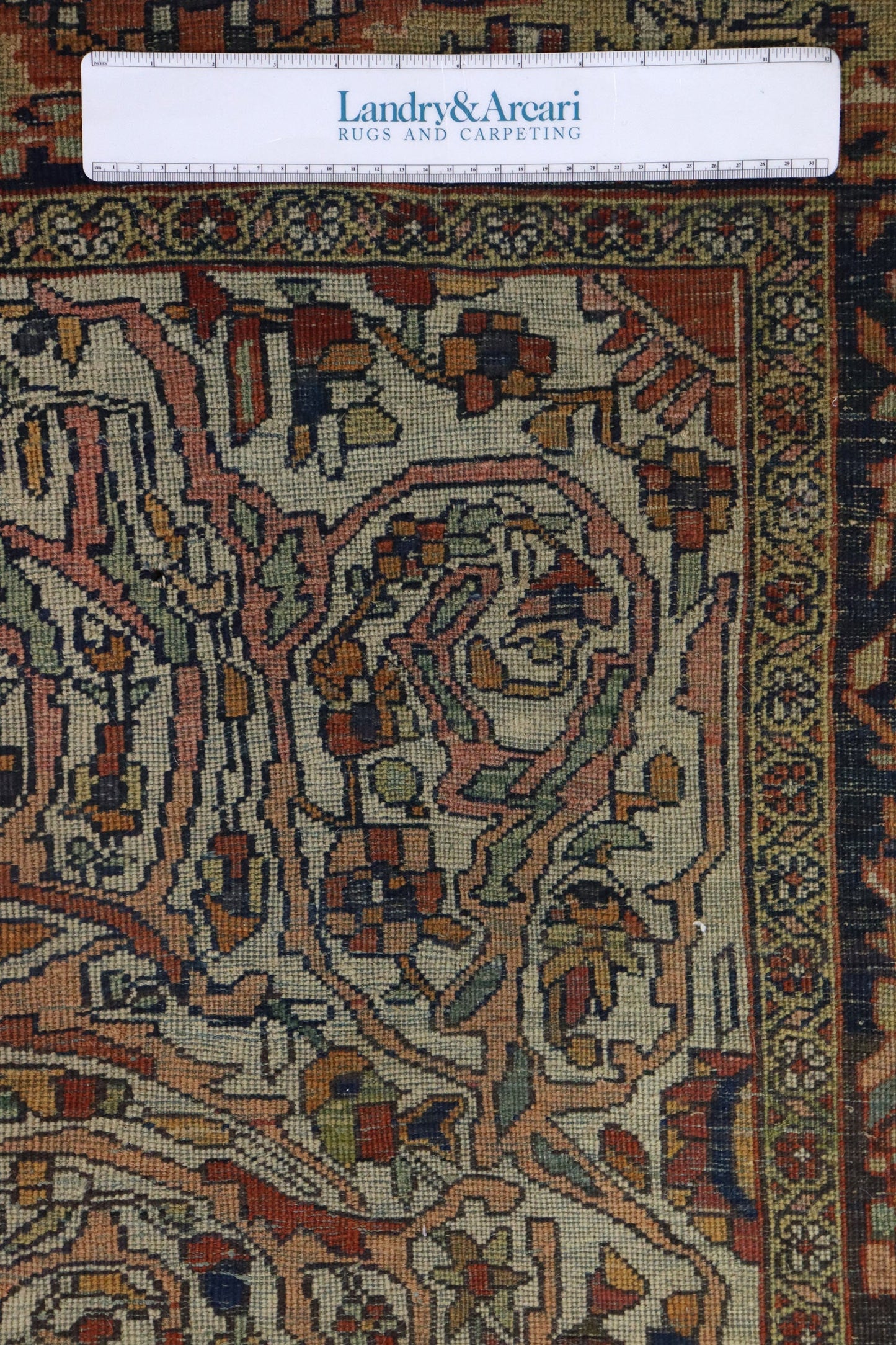 Close-up detail of antique Ferahan Sarouk rug's intricate, handwoven pattern in muted reds, greens, and beige.