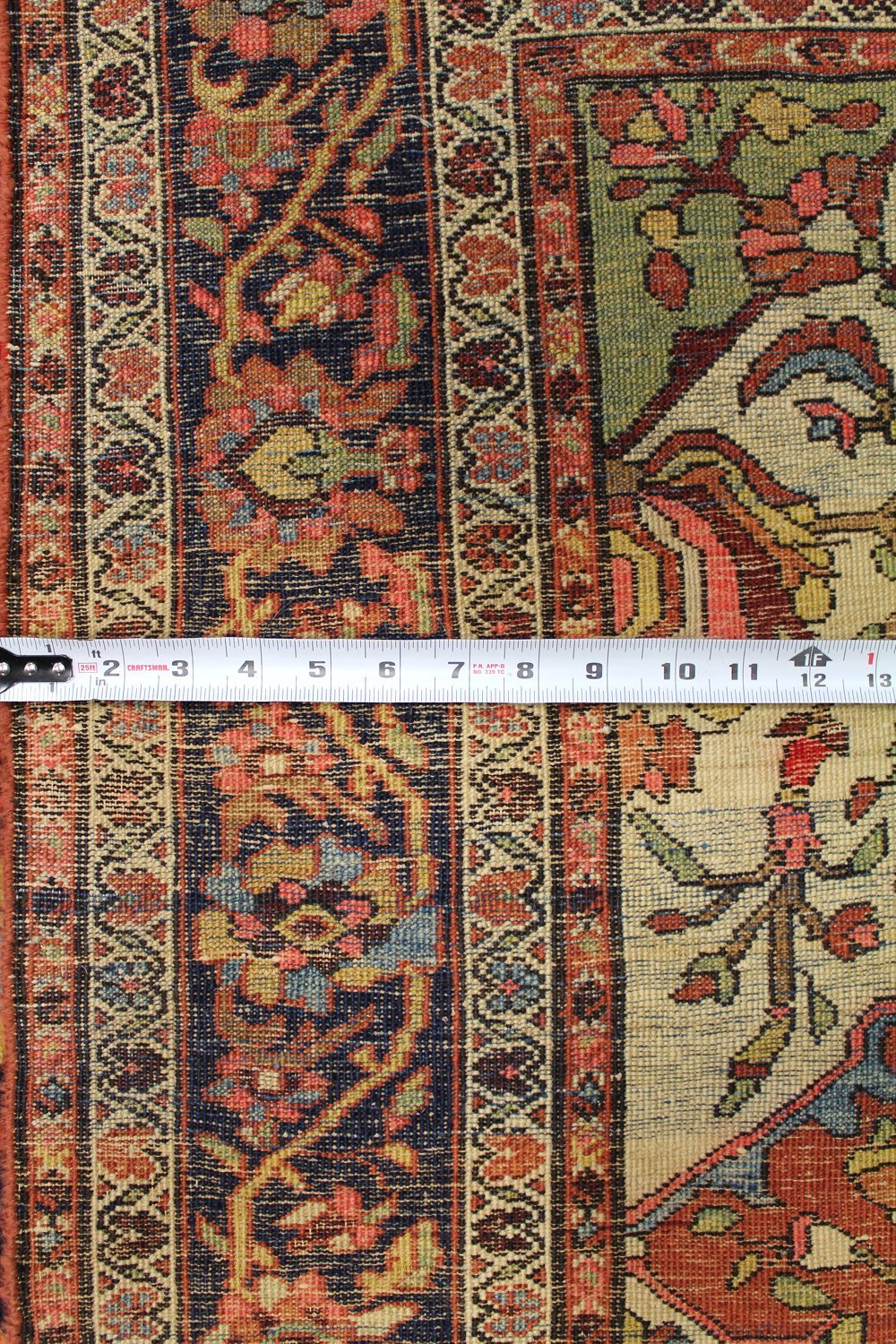 Antique Ferahan Sarouk rug detail, showcasing intricate handwoven floral patterns in muted reds, blues, and creams.