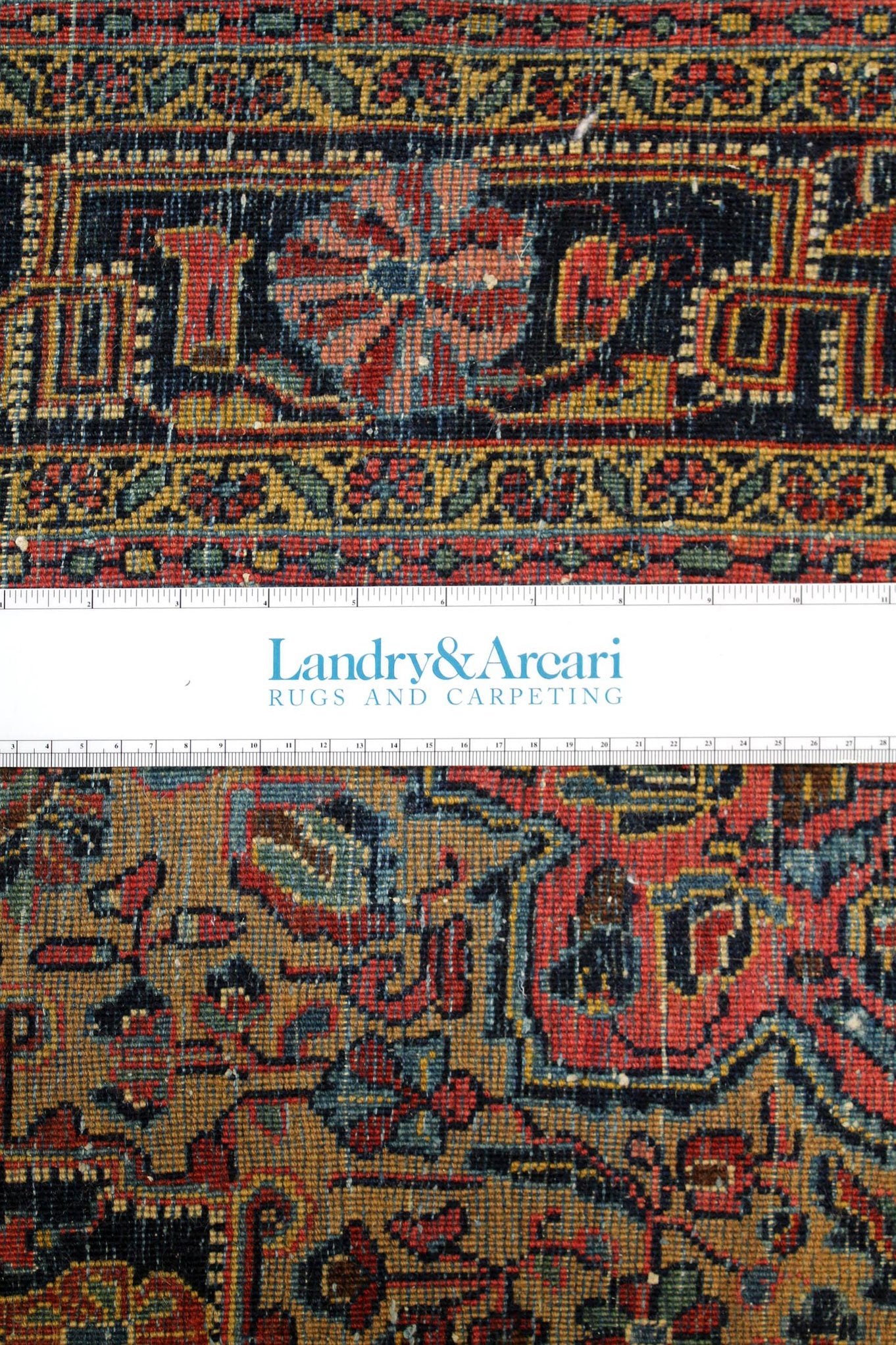 Close-up detail of antique Sarouk rug's intricate, handwoven pattern in rich reds, blues, and golds.