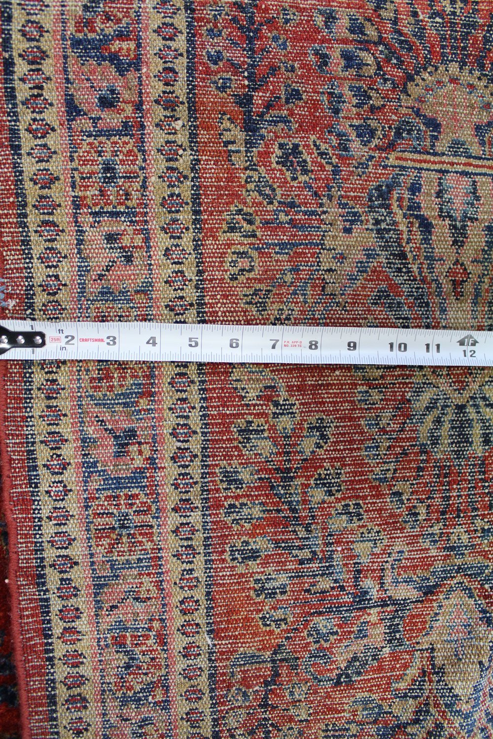 Detail of antique Lilihan rug, showcasing handwoven floral pattern in red, beige, and navy; measuring approximately 11 inches wide.