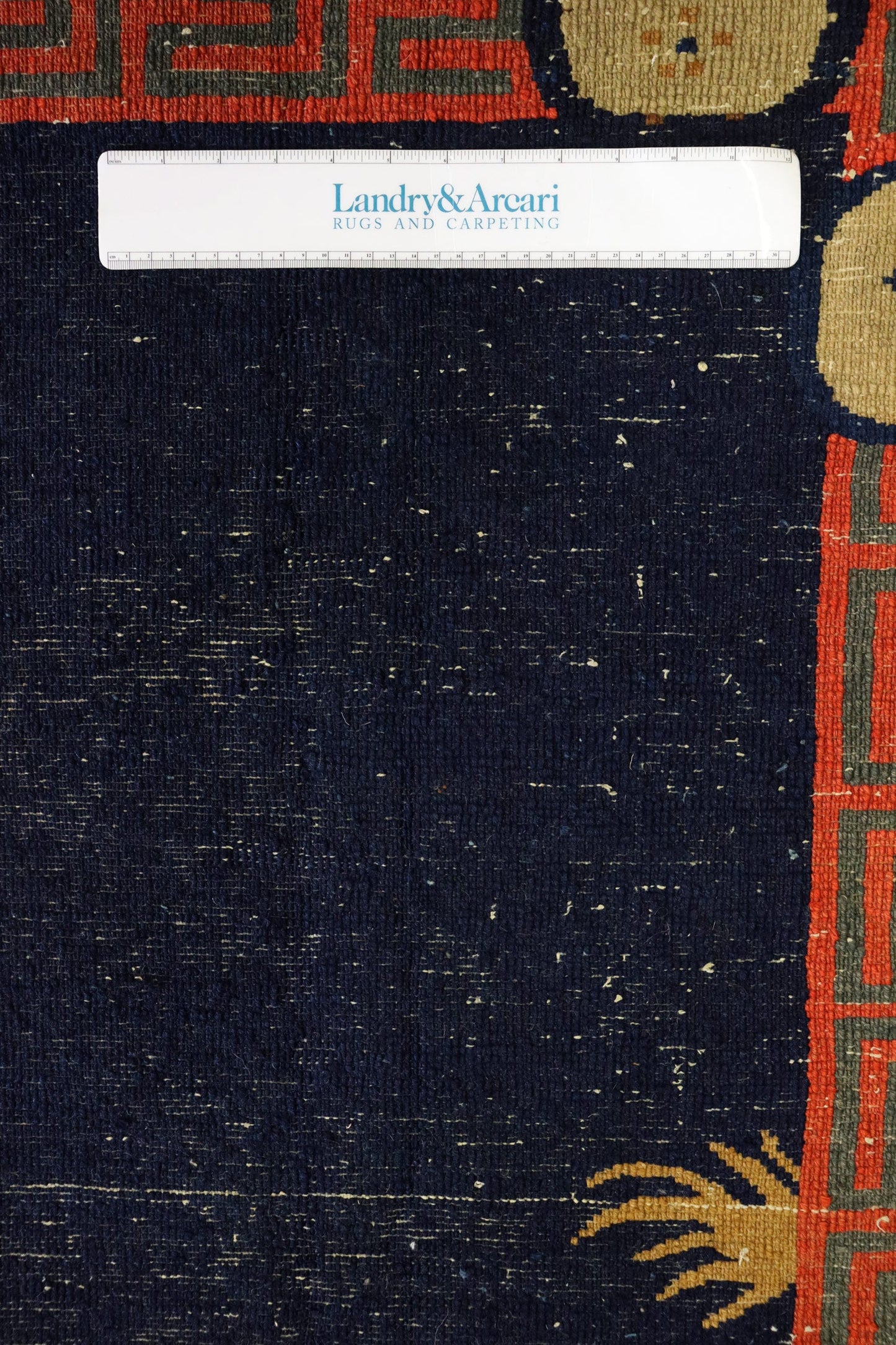 Close-up detail of antique Peking rug's handwoven texture, showcasing deep blue tones and intricate border.