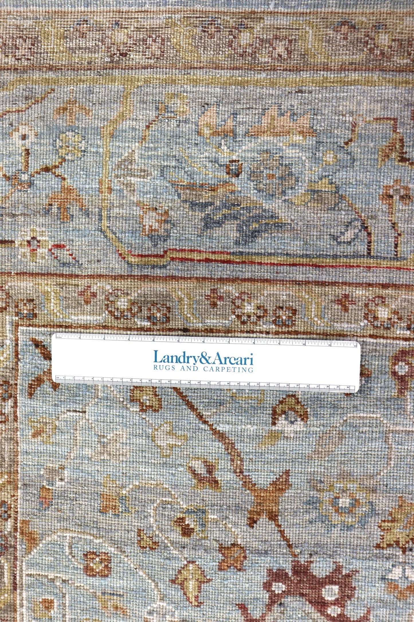 Close-up of handwoven rug detail, showing intricate pastel floral pattern.