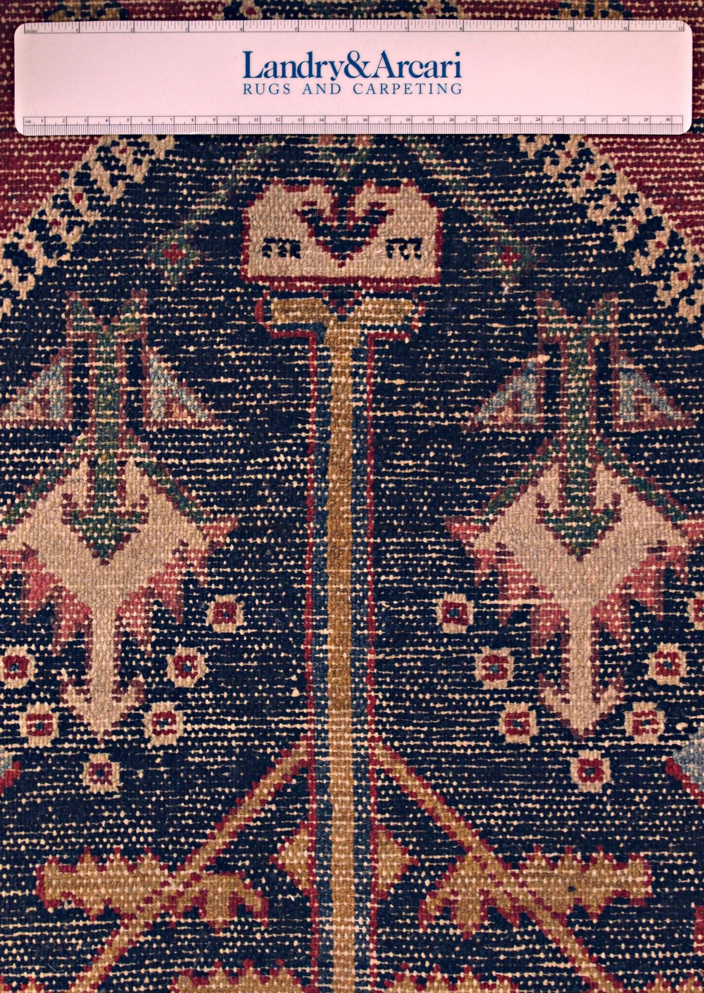 Close-up detail of antique Bakhtiari rug's intricate, handwoven pattern in rich navy, beige, and red tones.