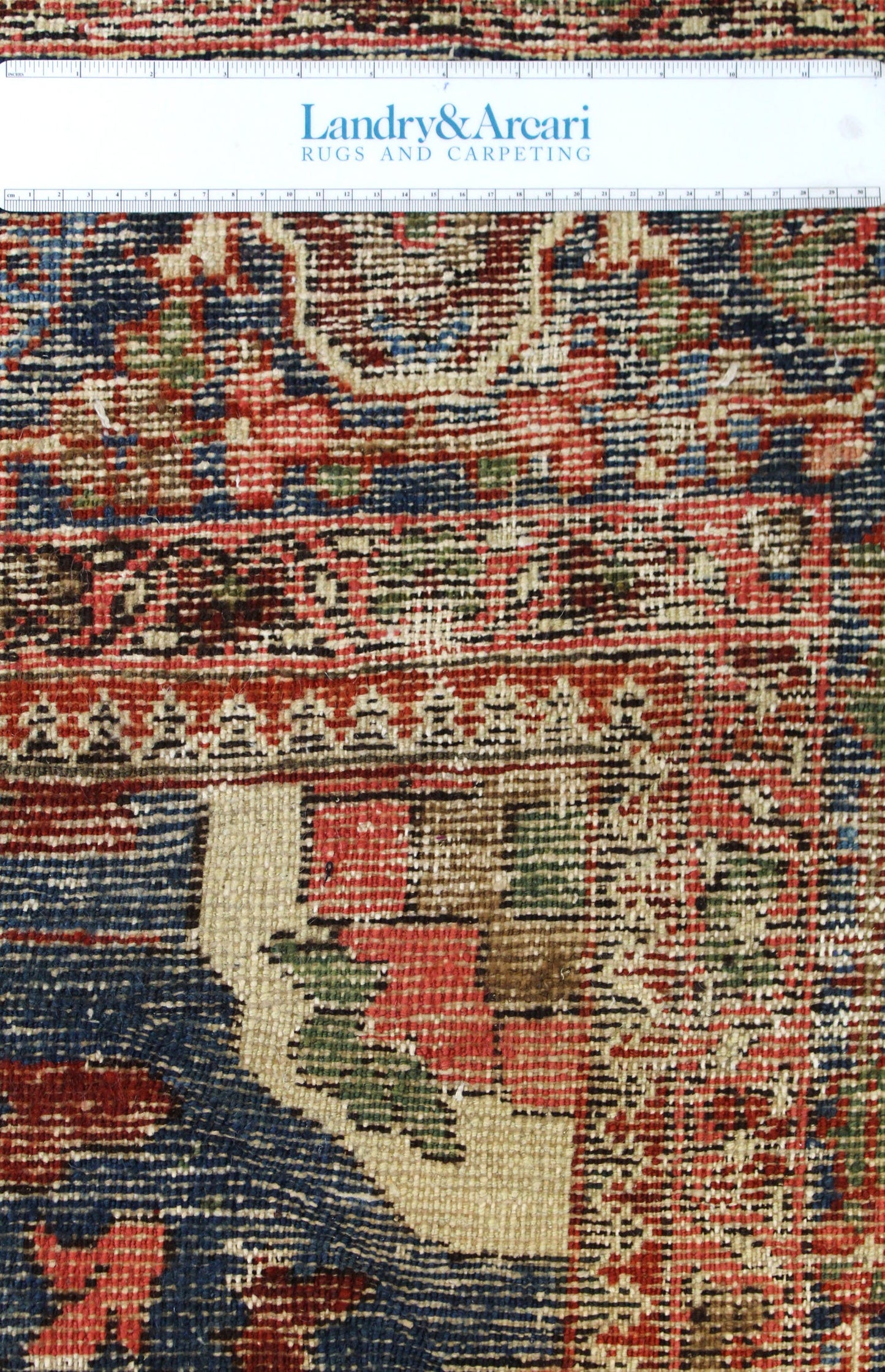 Detailed close-up of antique tribal rug's handwoven texture, showcasing rich reds, blues, and creams.