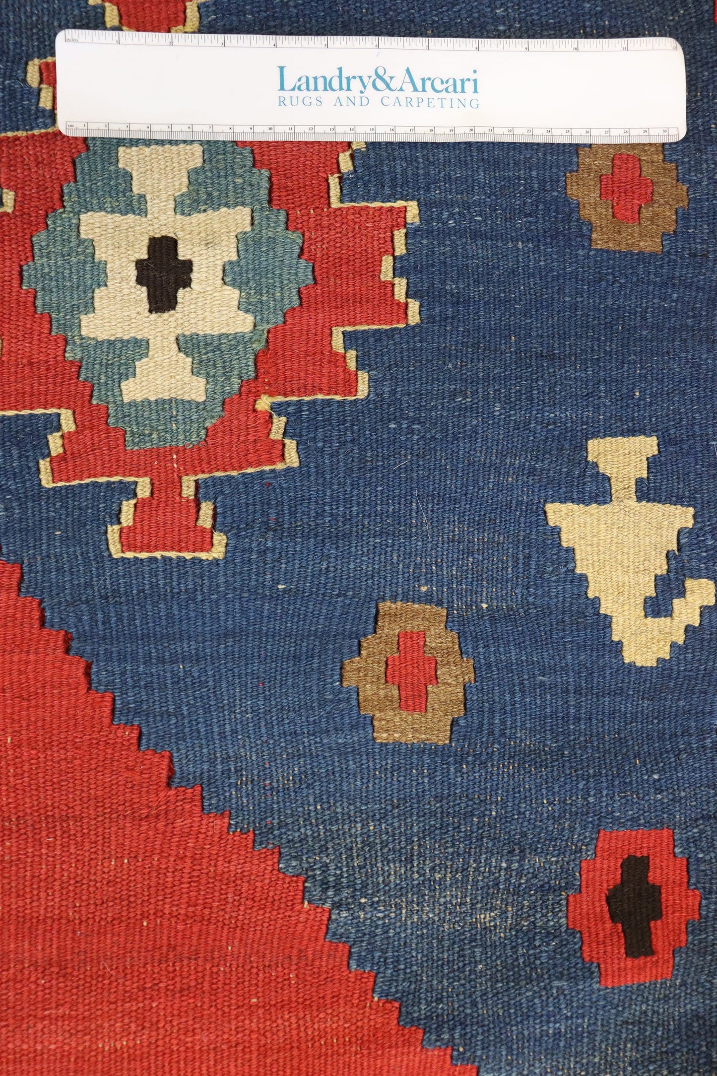 Close-up detail of a handwoven rug's intricate pattern, showcasing deep blues and reds.