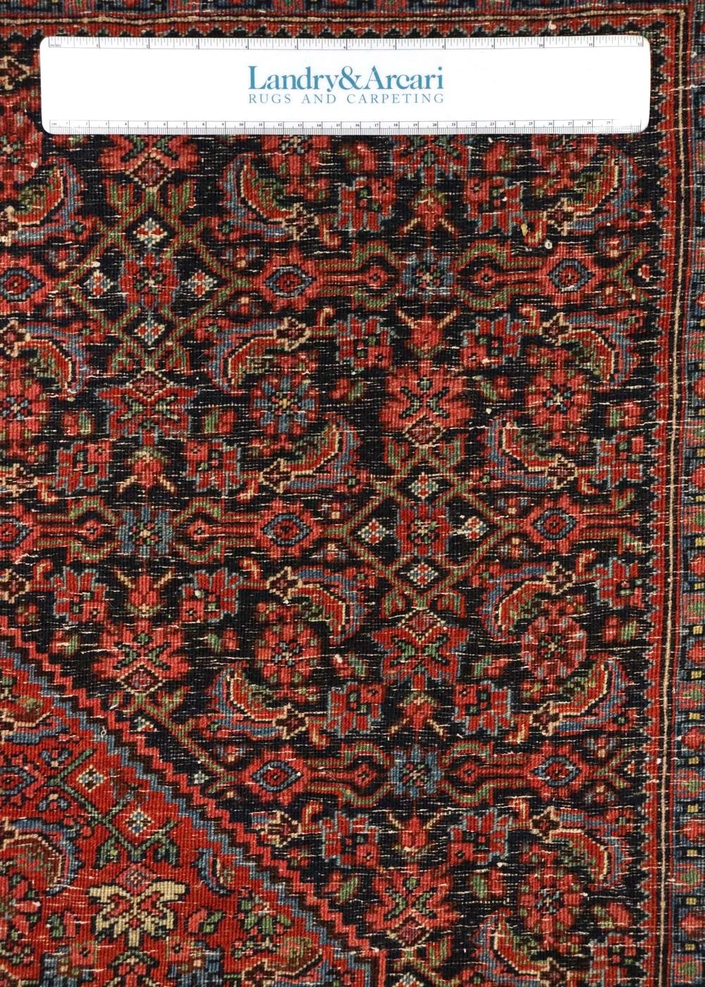 Close-up detail of antique Bijar rug's intricate, red and black handwoven pattern.