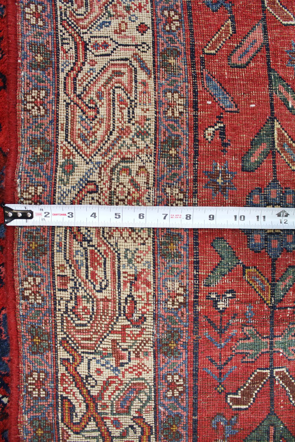 Close-up detail of antique Bijar rug's border, showcasing intricate handwoven pattern and rich red hues.