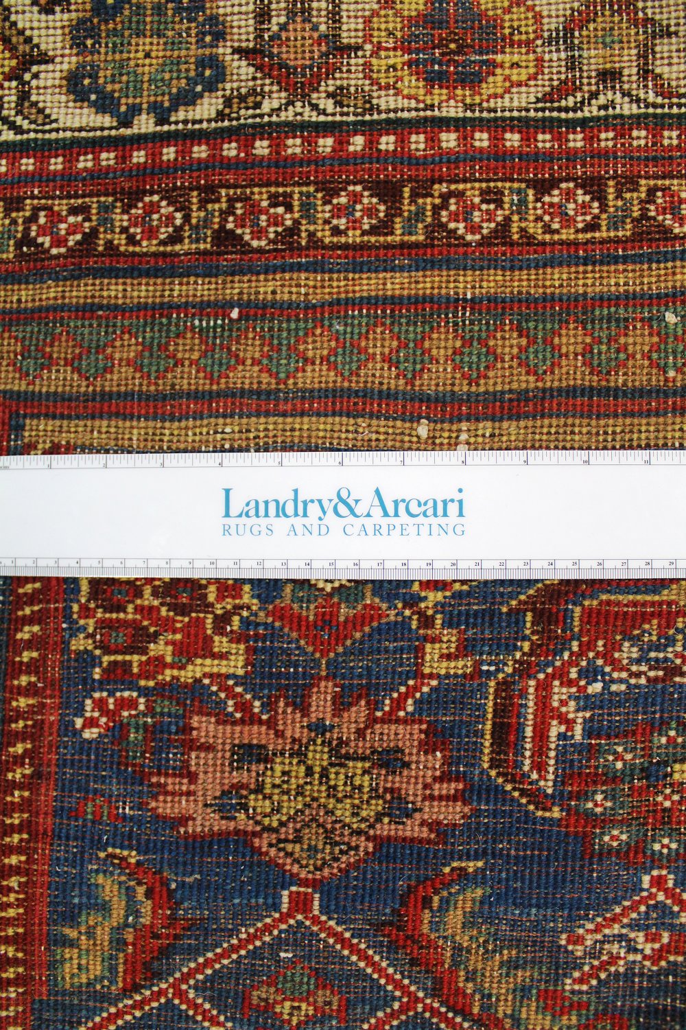 Close-up detail of an antique Bijar rug's intricate, handwoven pattern—featuring rich reds, blues, and golds.