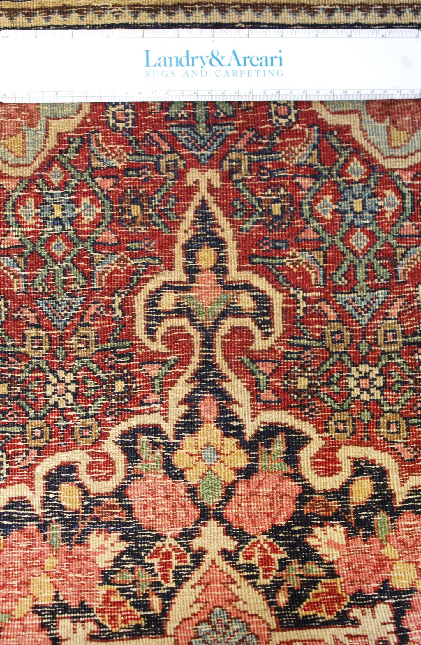 Close-up detail of an antique Bijar rug's intricate, handwoven floral pattern in red, beige, and navy.