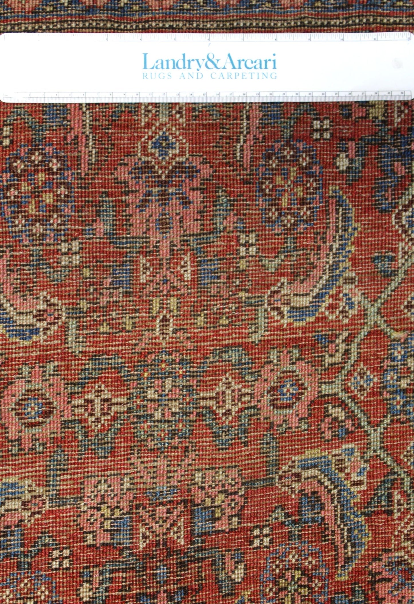 Close-up detail of antique Bijar rug's intricate, handwoven pattern in red, blue, and beige tones.