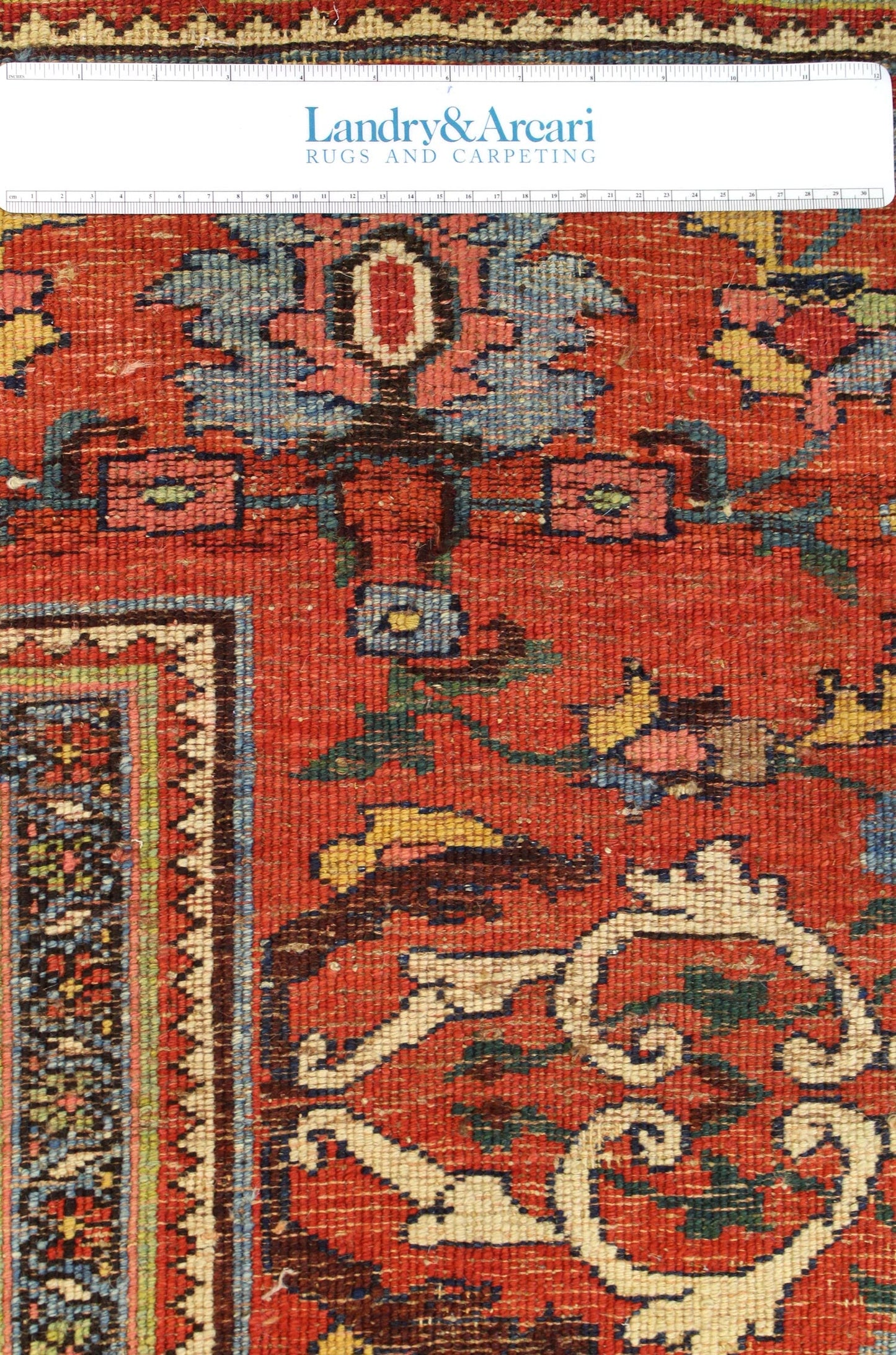 Close-up detail of a red antique Bijar rug, showcasing its intricate handwoven floral pattern and border.