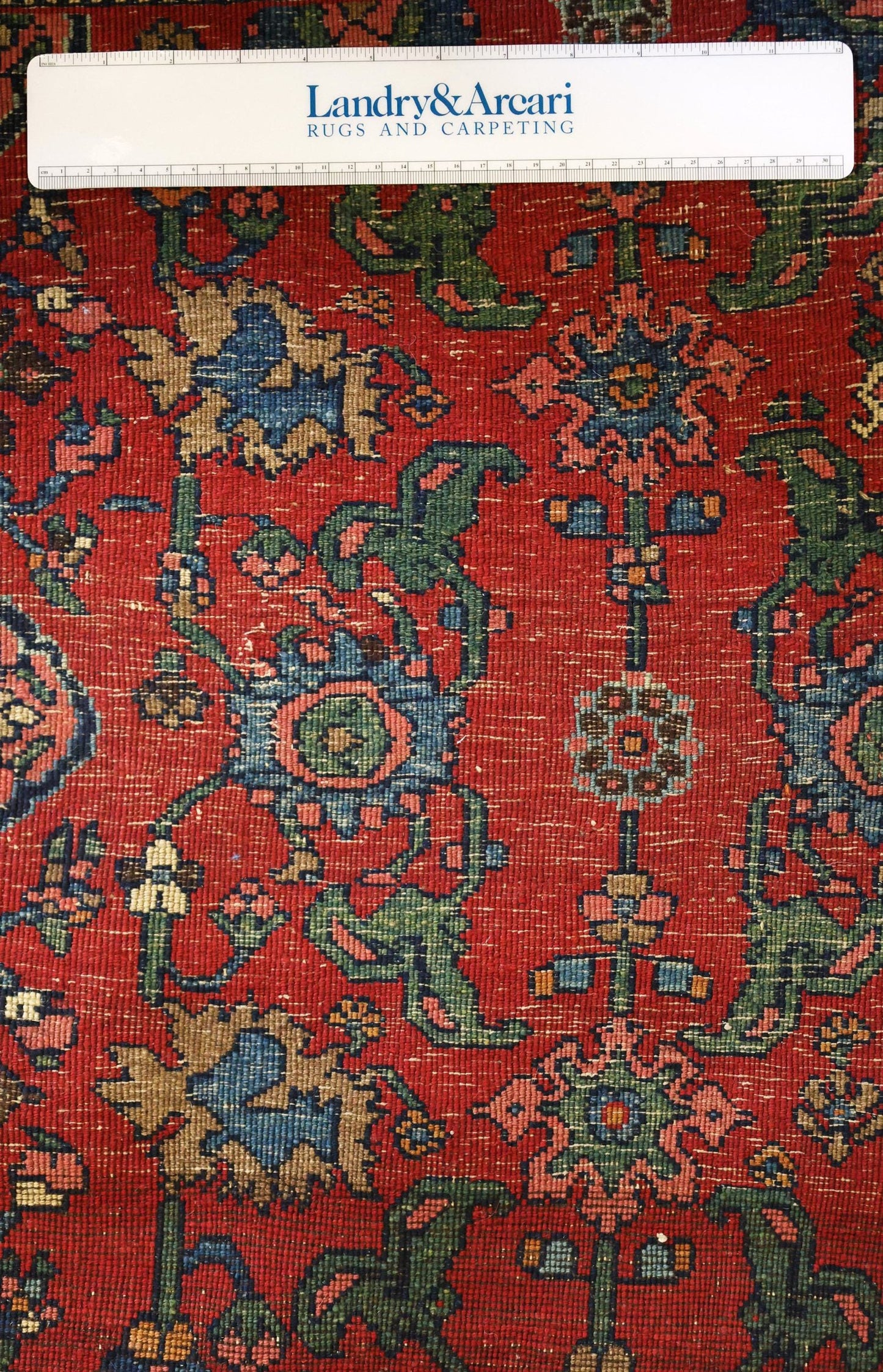 Detailed close-up of a red antique Bijar rug showcasing intricate floral patterns in blue, green, and pink.