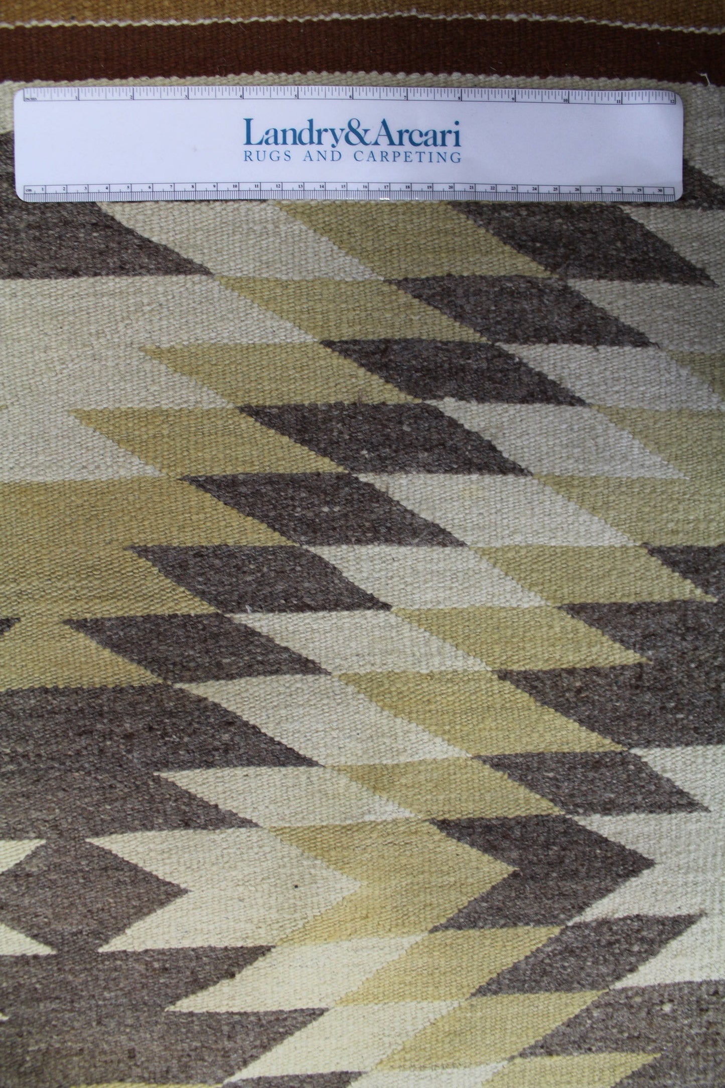Handwoven rug detail, showcasing a geometric pattern in beige, brown, and off-white.