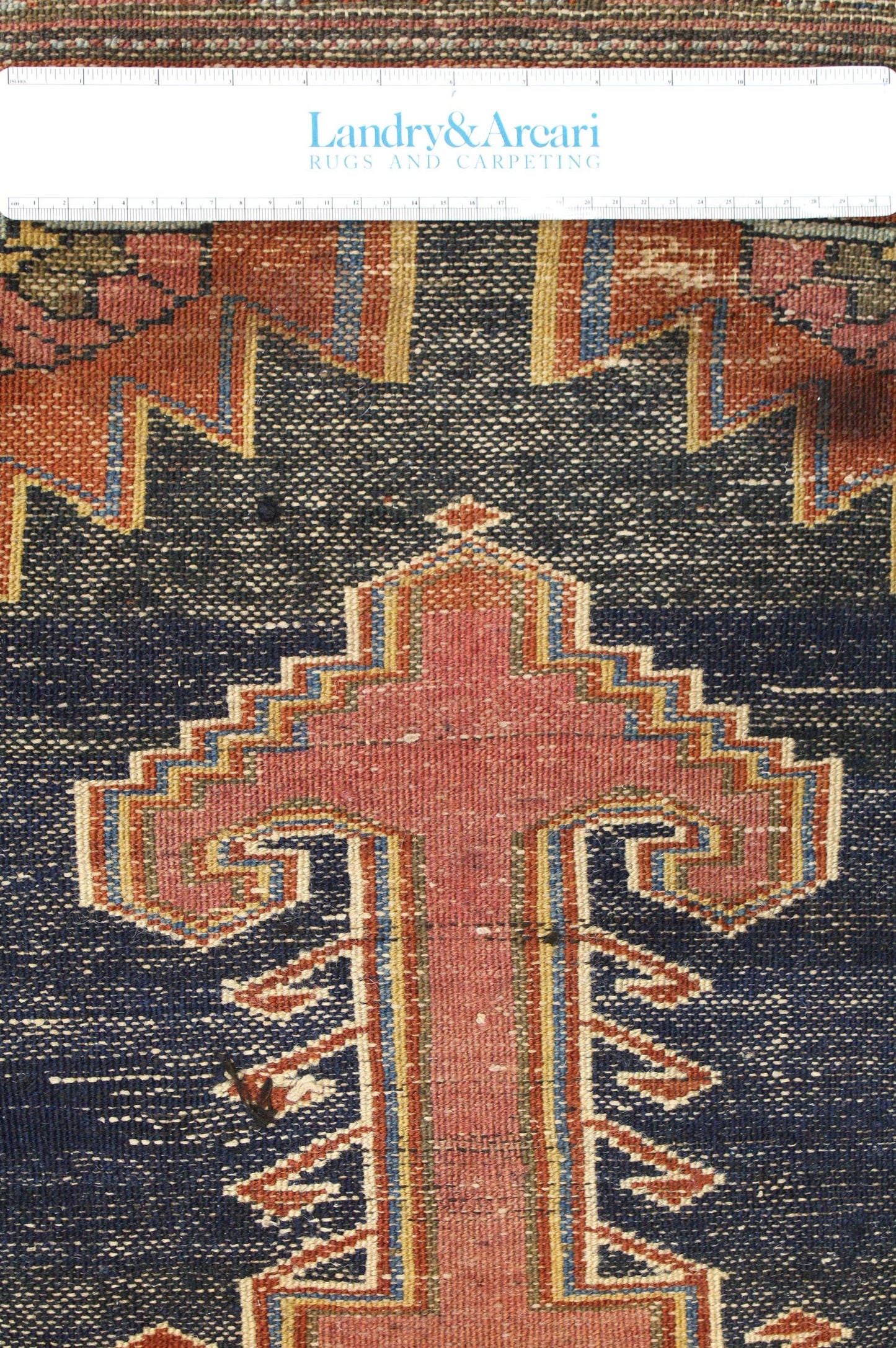Close-up detail of antique Hamadan rug's handwoven pattern, showcasing rich reds and blues.