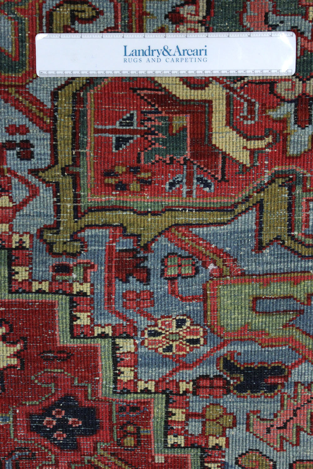 Close-up detail of antique Heriz rug's handwoven, richly colored pattern.