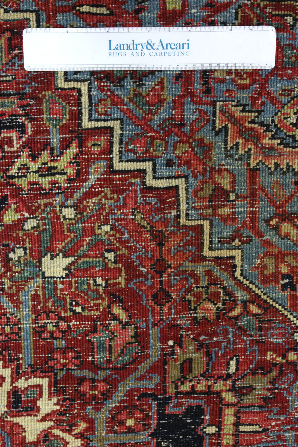 Close-up detail of antique Heriz rug's intricate, handwoven design in red, blue, and ivory.