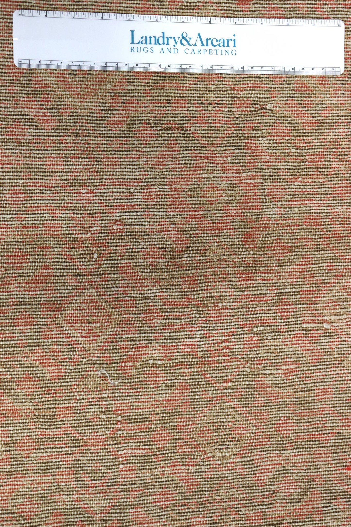 Close-up of handwoven rug's detailed texture, featuring muted reds and browns.