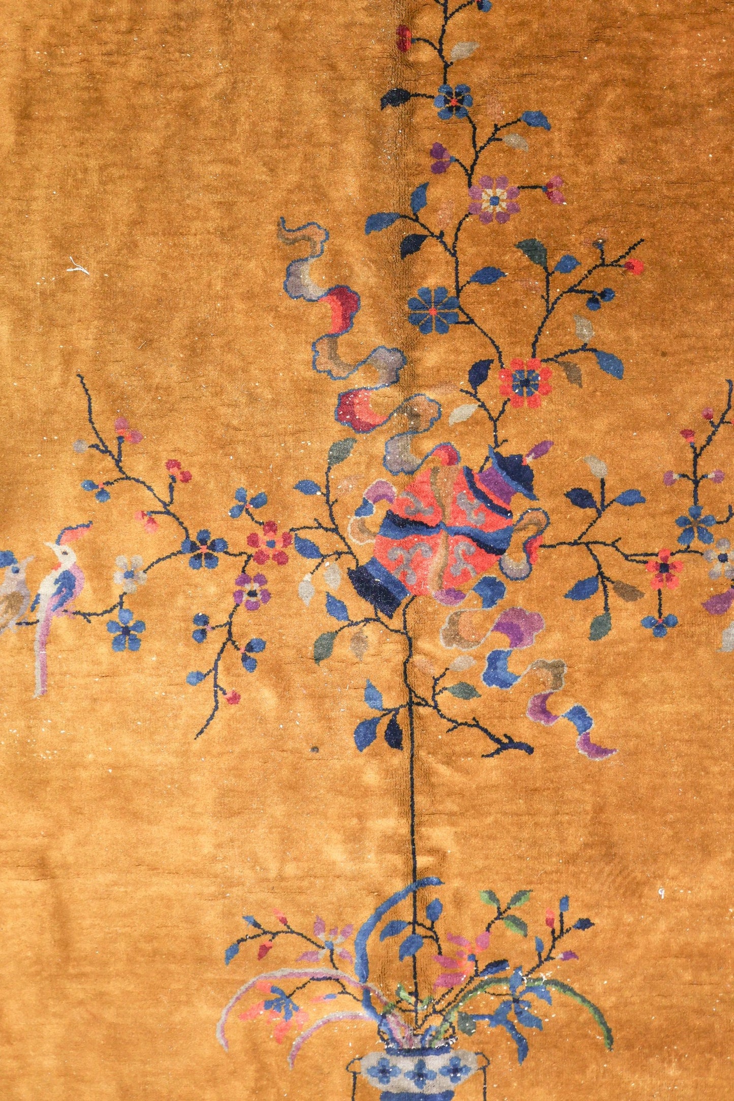 Handwoven Art Deco rug in gold, detailed with a floral motif and birds.
