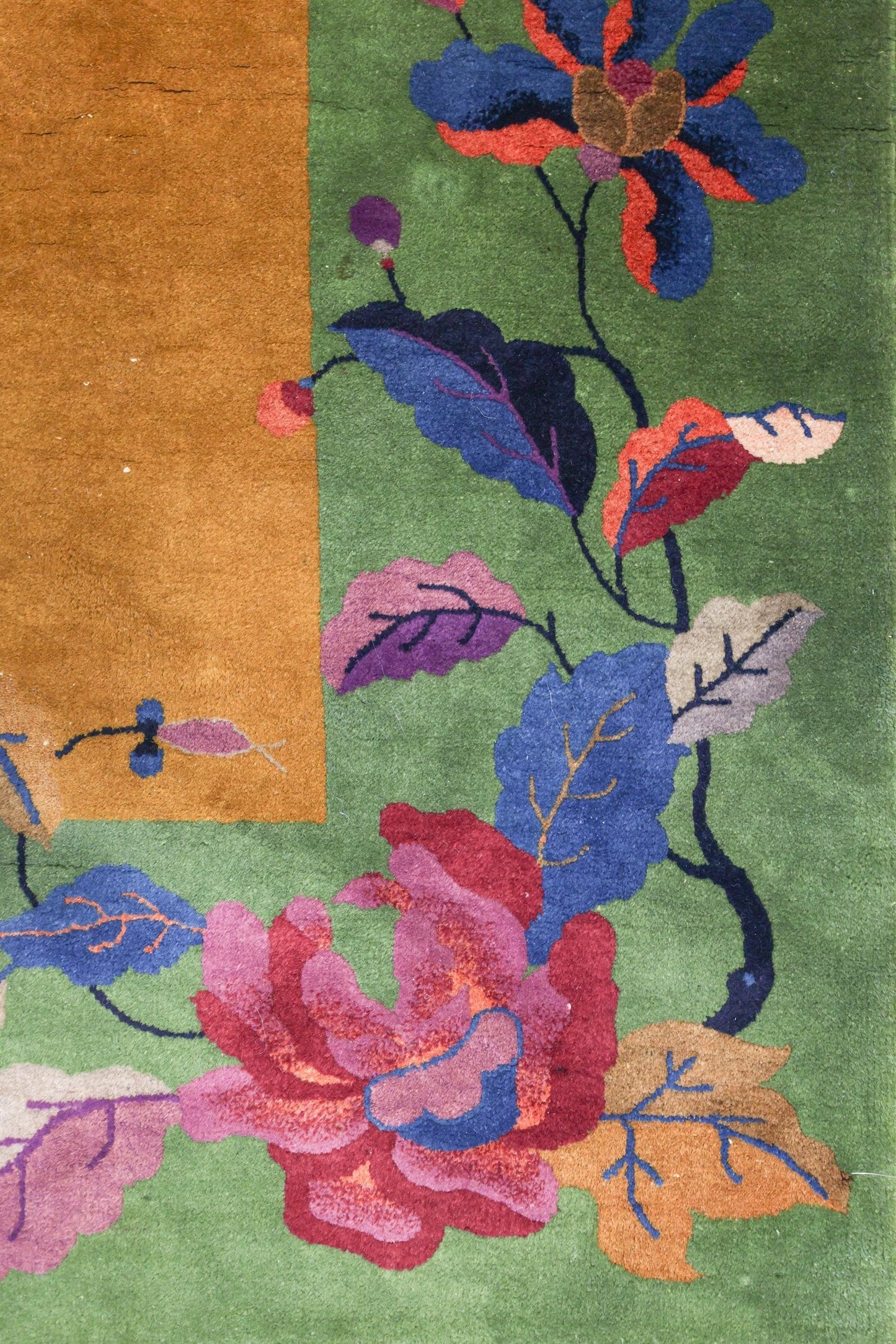 Handwoven Art Deco rug detail: vibrant floral pattern on green background, featuring multicolored roses and leaves.
