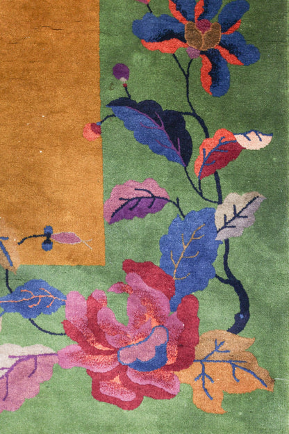 Handwoven Art Deco rug detail: vibrant floral pattern on green background, featuring multicolored roses and leaves.
