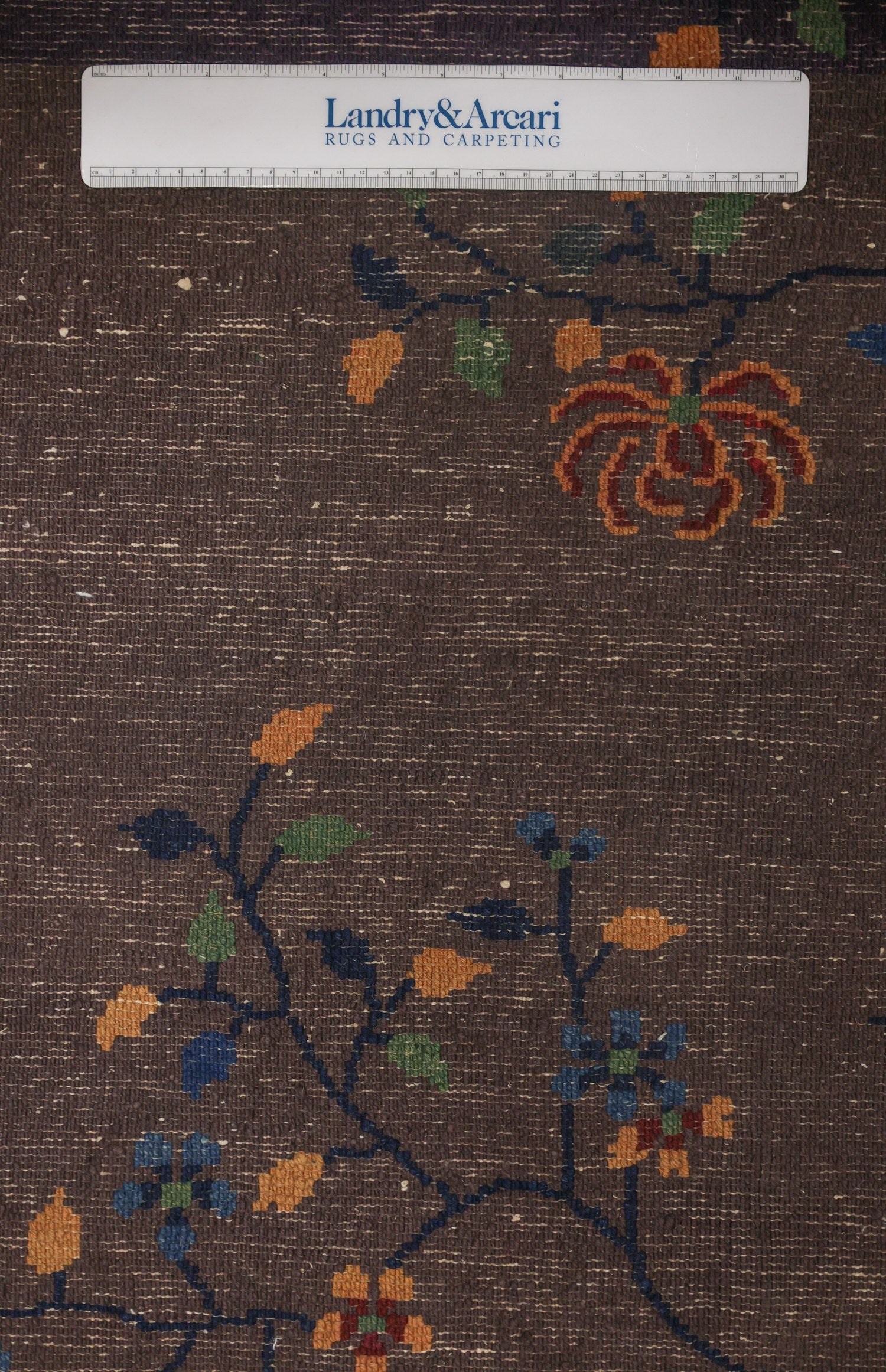Close-up of an antique Art Deco rug's handwoven floral pattern in muted tones.
