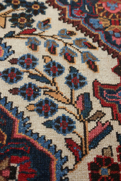 Close-up of antique rug detail, showcasing handwoven floral pattern in blue, red, and beige.
