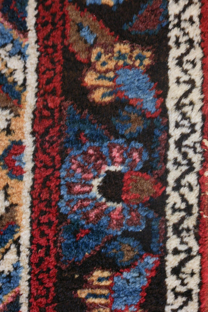 Close-up of handwoven rug detail; rich reds, blues, and creams in a traditional pattern.
