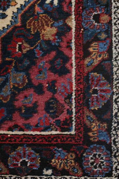 Handwoven rug detail, showcasing rich reds, blues, and creams in a traditional pattern.
