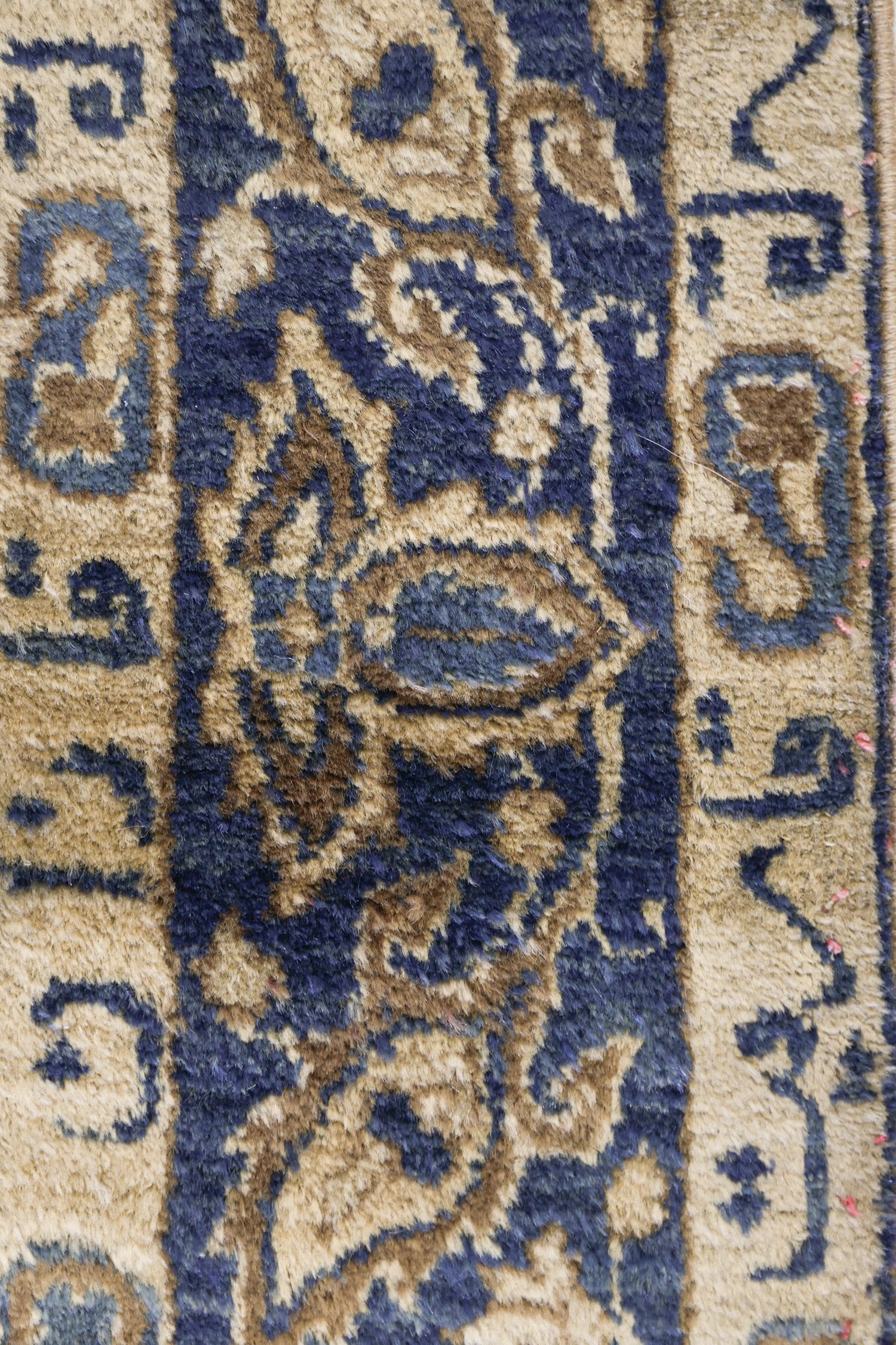 Close-up detail of a handwoven rug with a beige and navy blue pattern.
