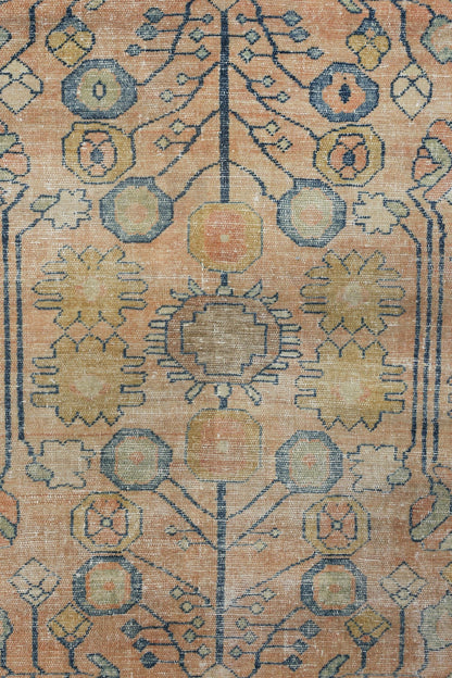 Close-up of an antique Lilihan rug’s handwoven, traditional design in muted peach and blue tones.

