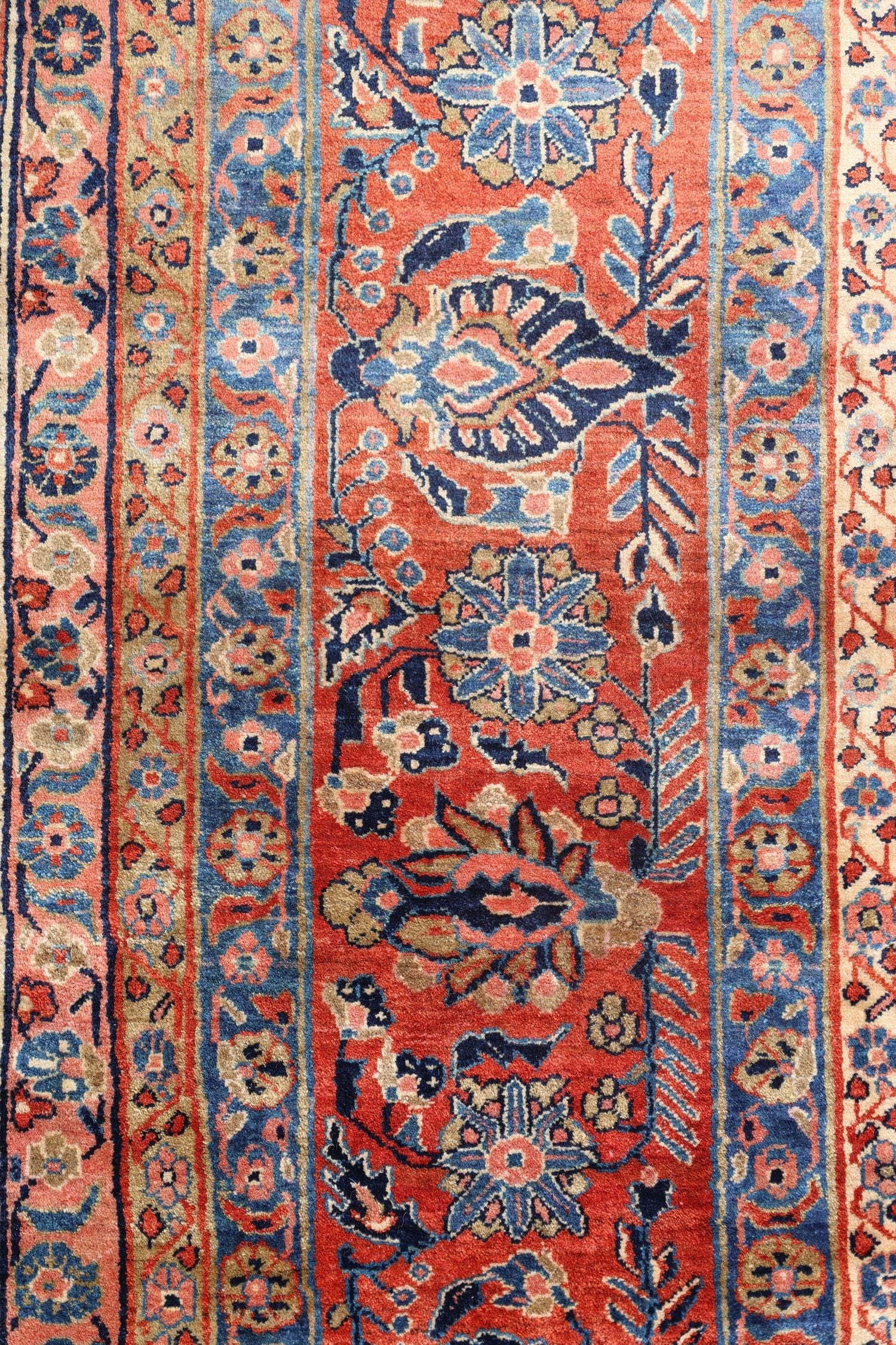 Detailed close-up of a traditional handwoven rug displaying intricate floral patterns in shades of red, blue, and beige.
