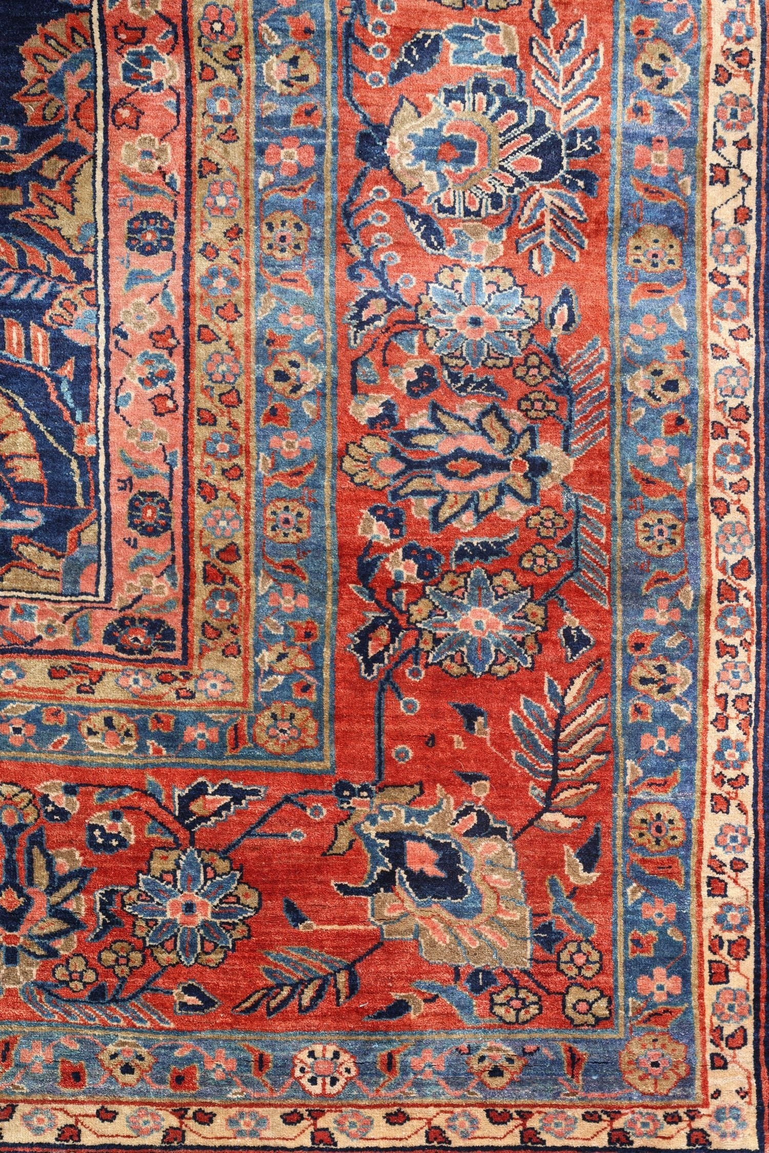 Detail of antique rug's handwoven floral border, showcasing rich reds, blues, and intricate patterns.
