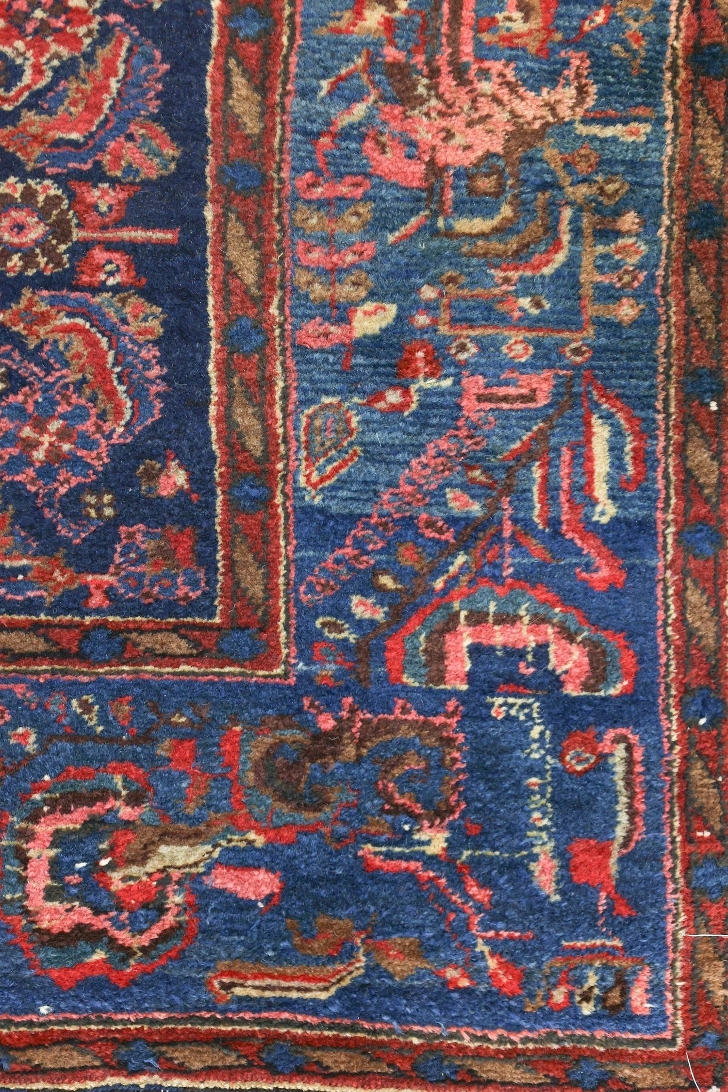 Detailed close-up of a handwoven Persian rug's intricate design, showcasing rich blues and reds.
