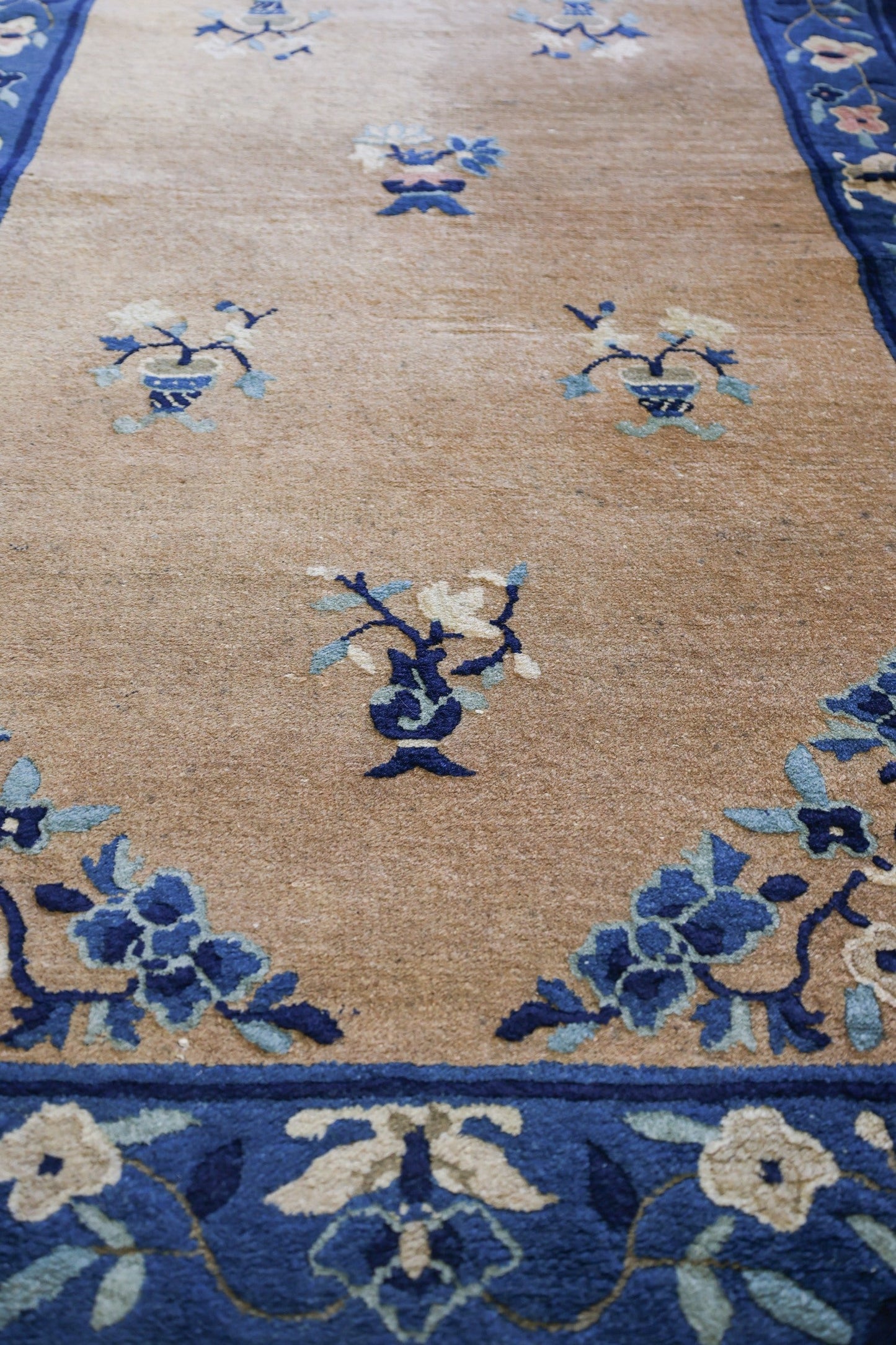 Tan handwoven rug with blue floral details, antique Peking design.
