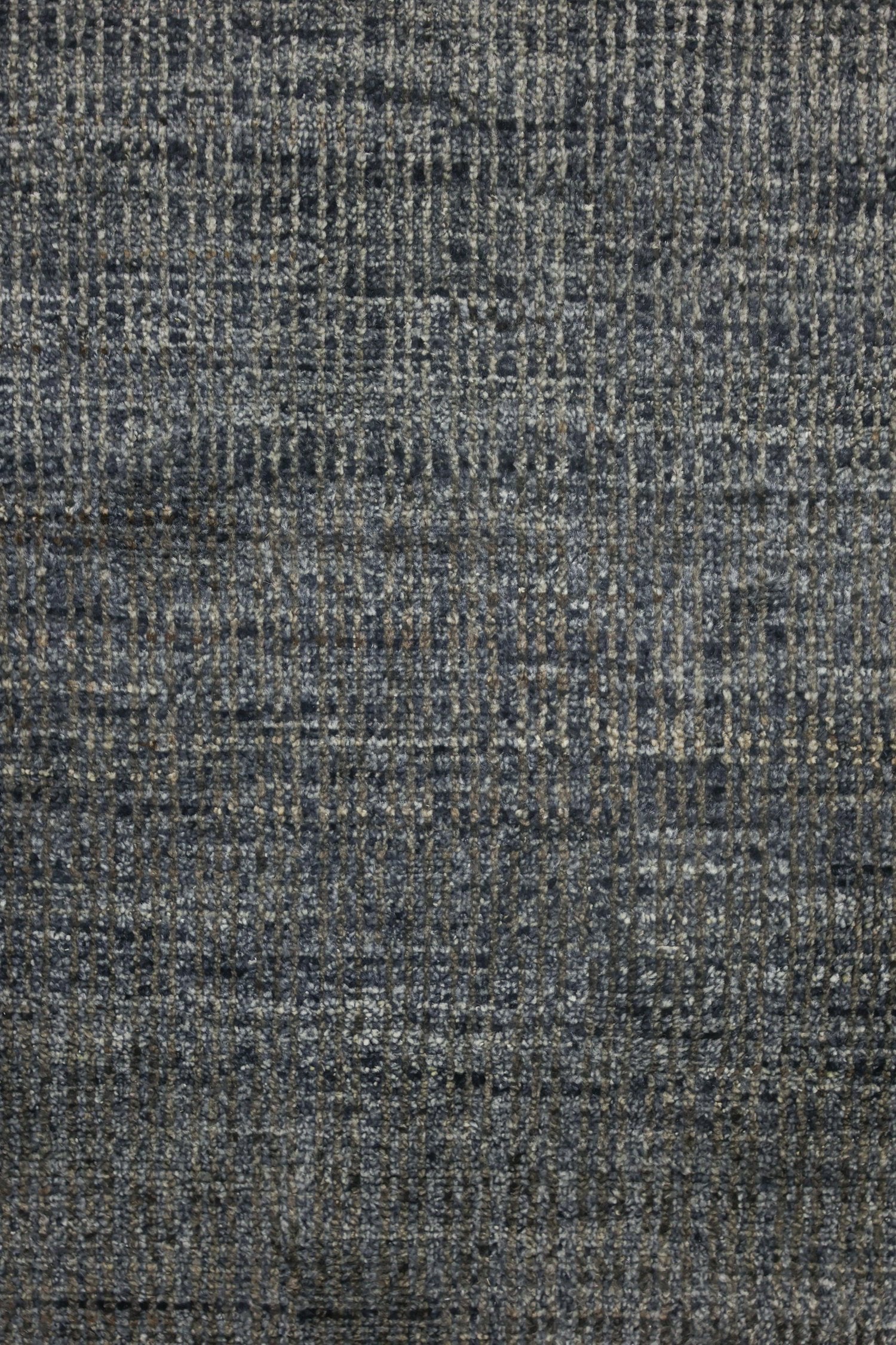 Close-up of handwoven rug's textured, abstract plaid pattern in grey and beige tones.
